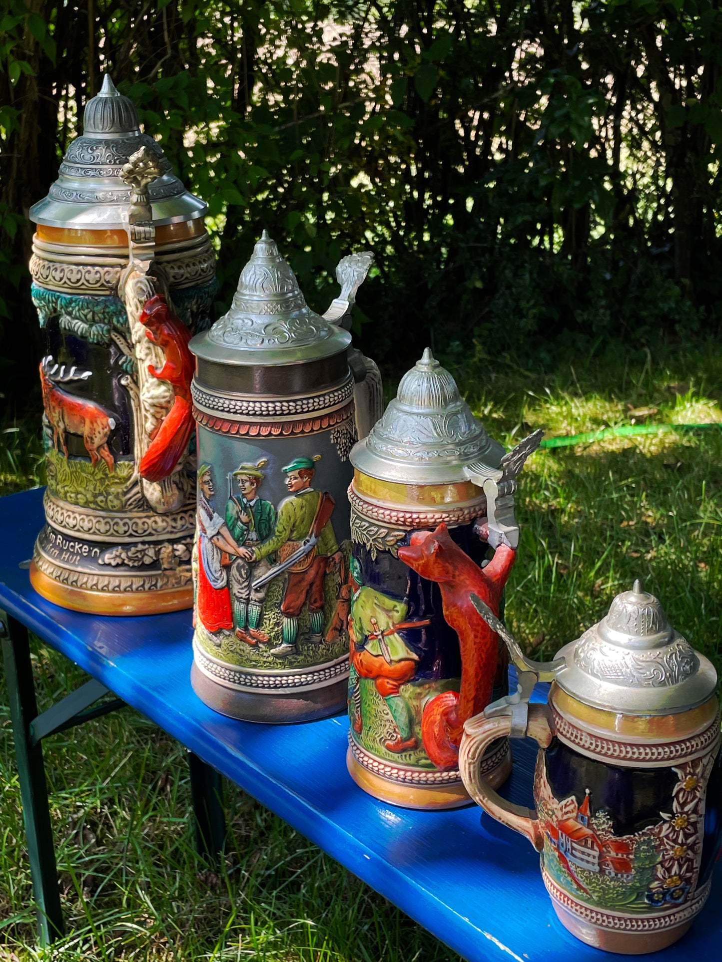 Three-quarter view of the four graduated relief beer steins with lids raised