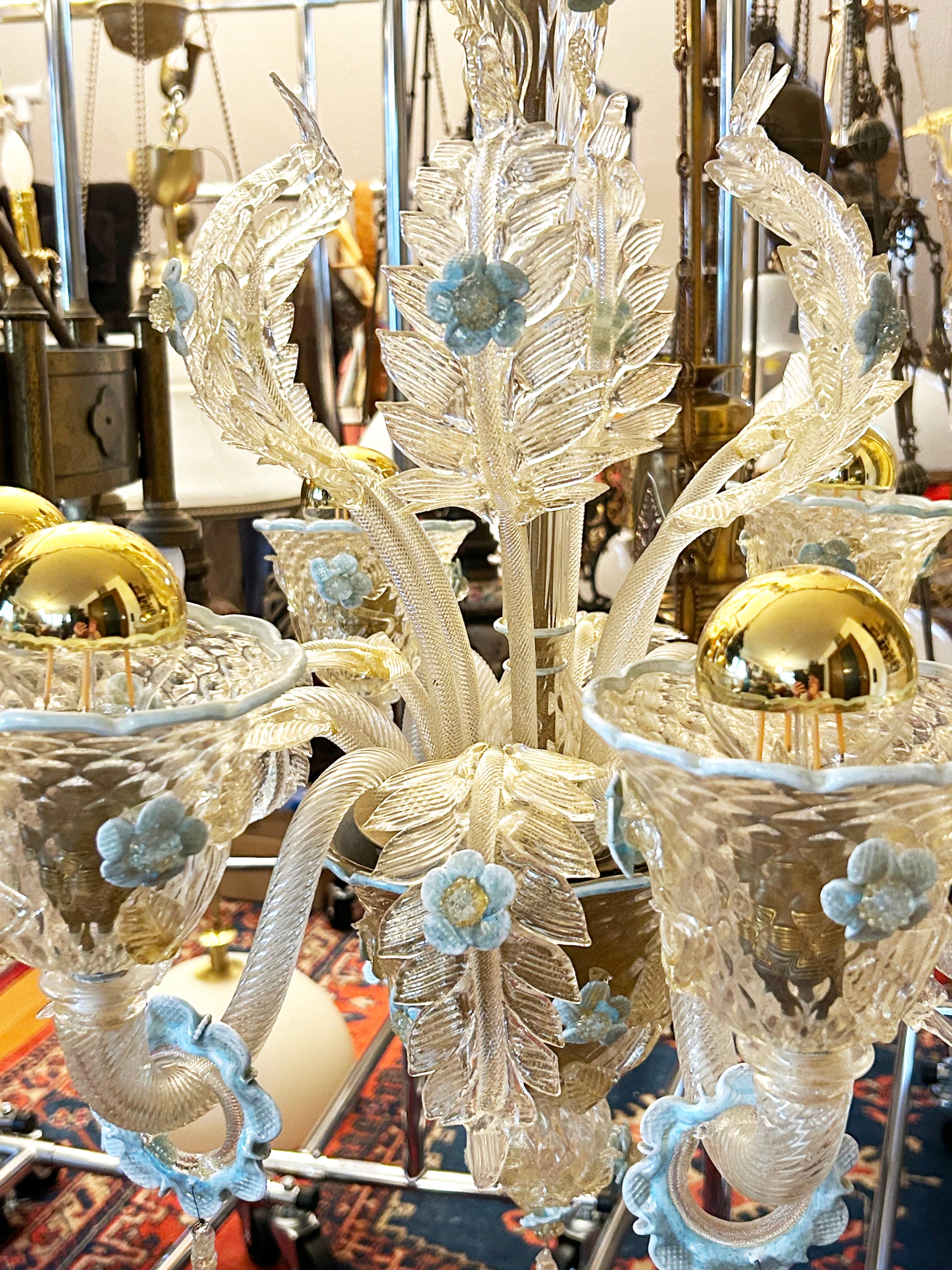 Close detail of a Murano candle cup with gold sphere and blue glass blossom