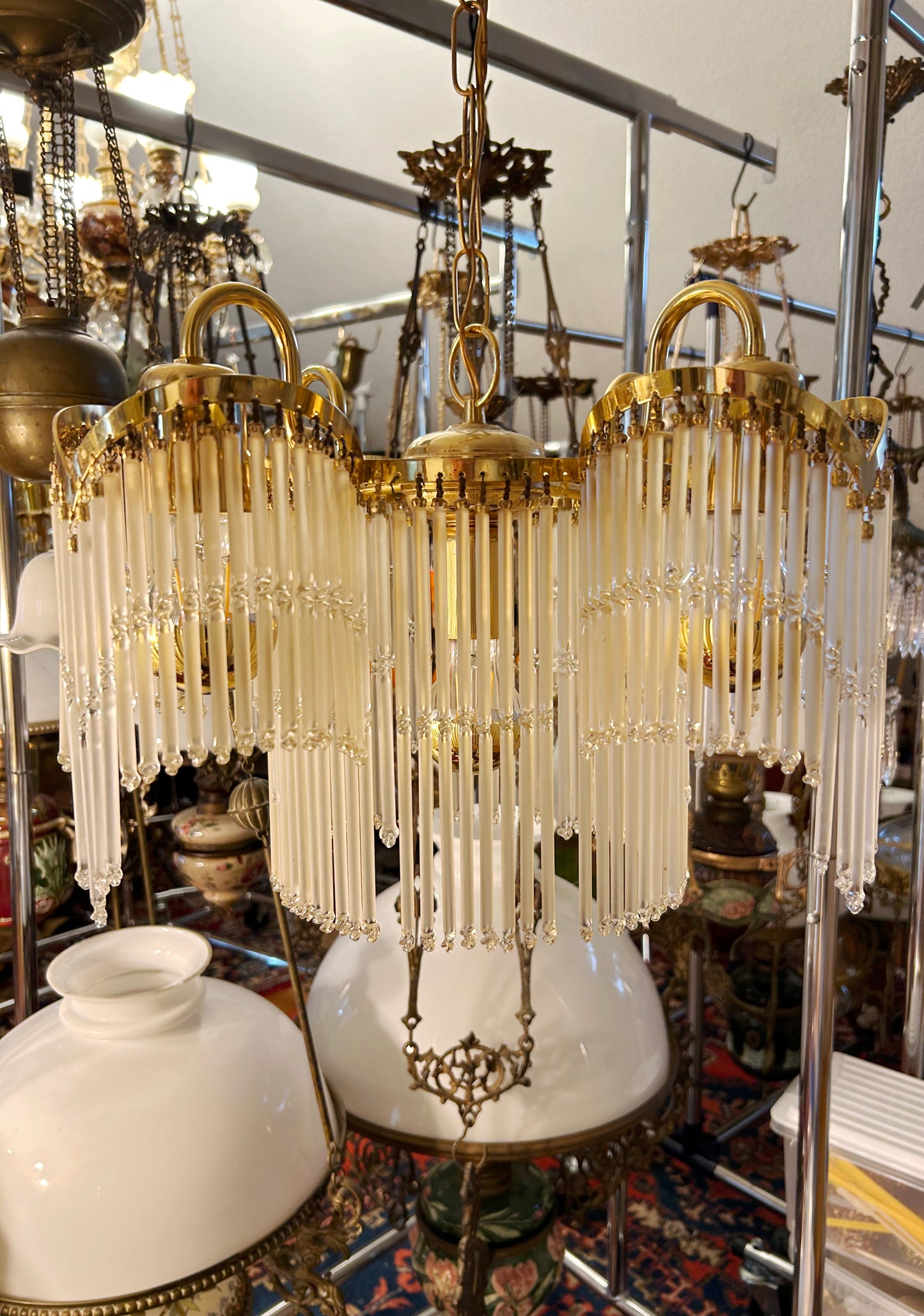 Three-quarter view of the brass and glass-rod chandelier showing the swagged silhouette