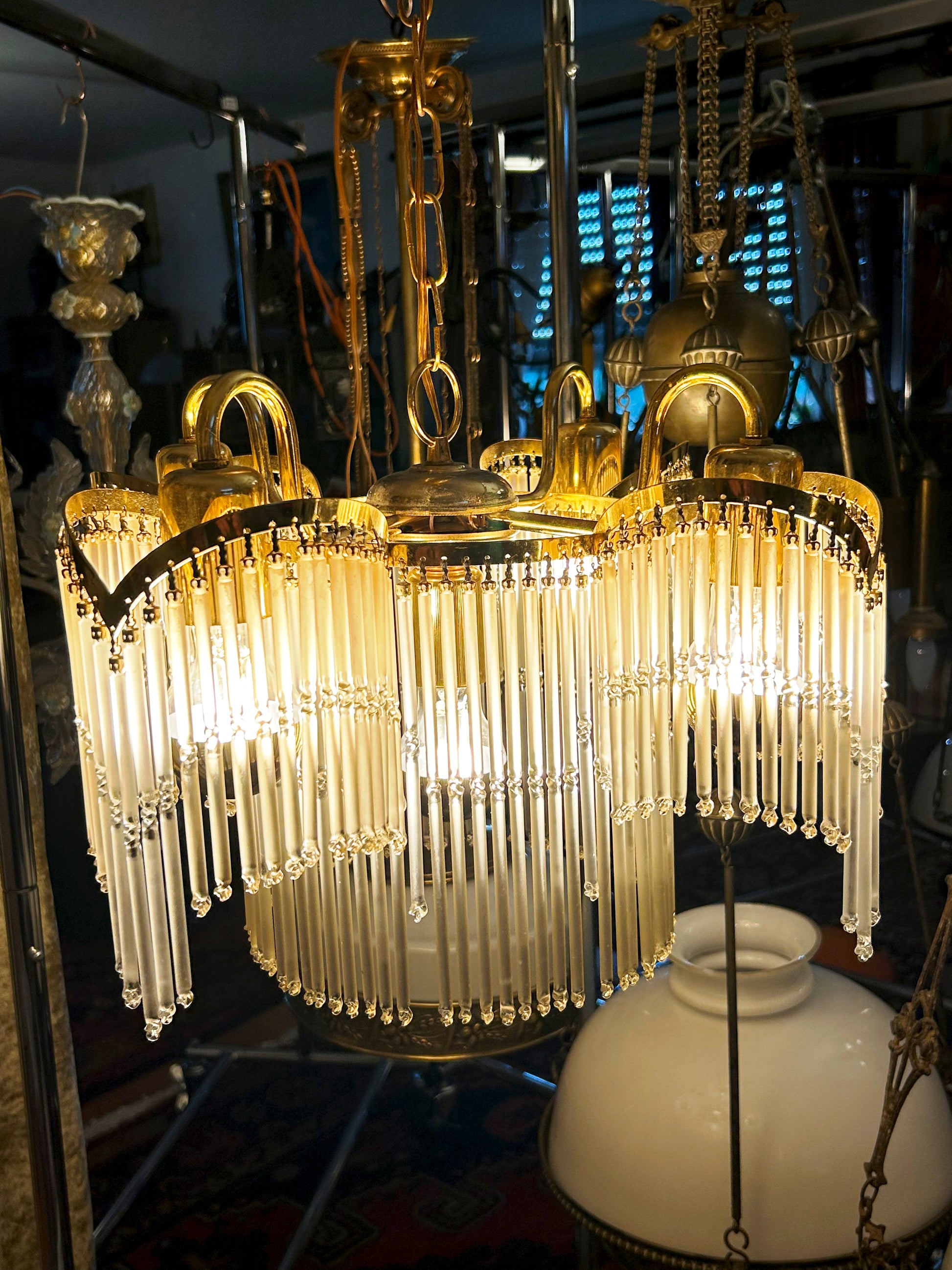 Glass-rod chandelier hanging and lit, full view of cascading crystal swags