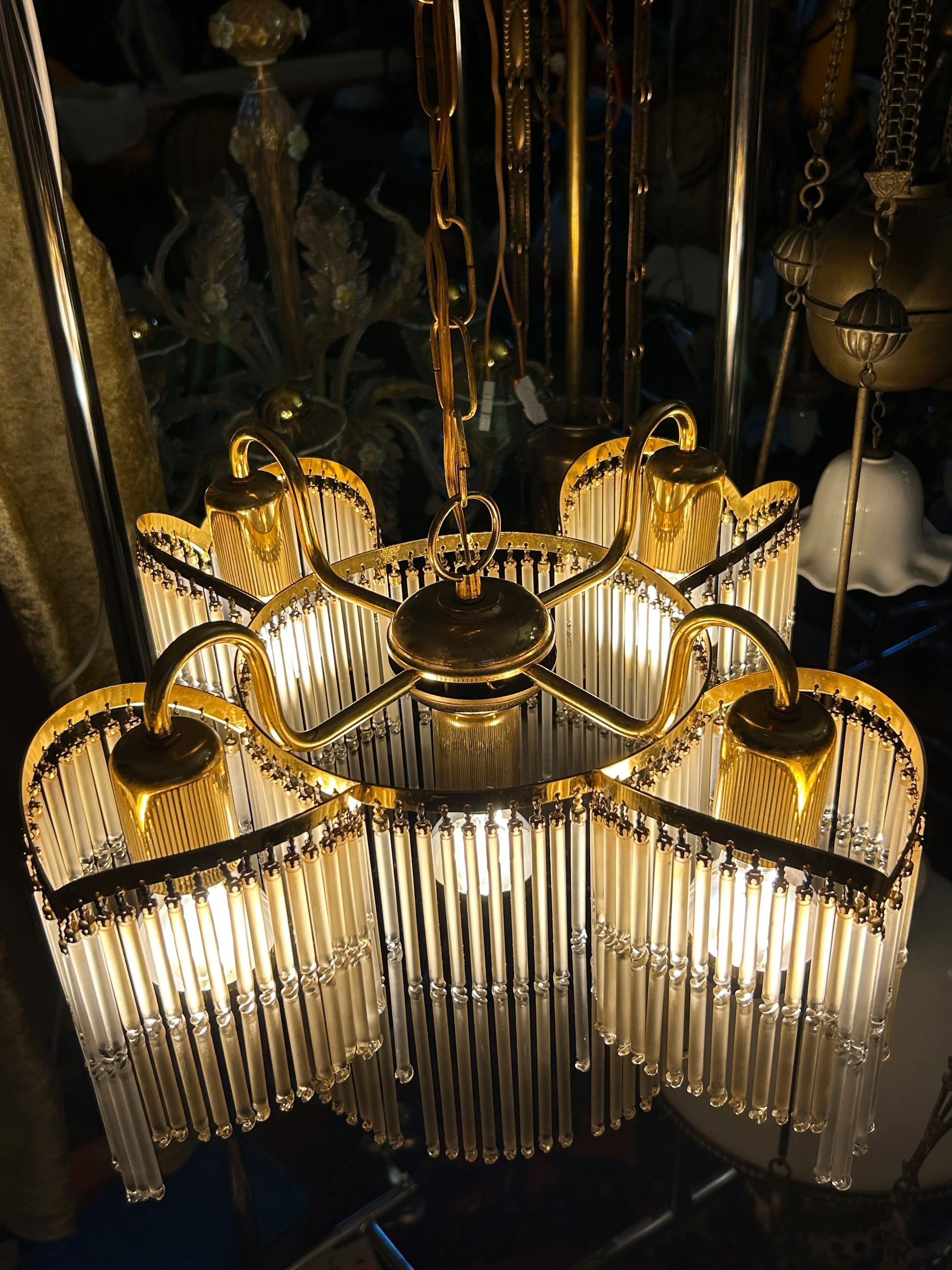 Four-arm brass chandelier viewed from below showing complete structure and glass rod fringe