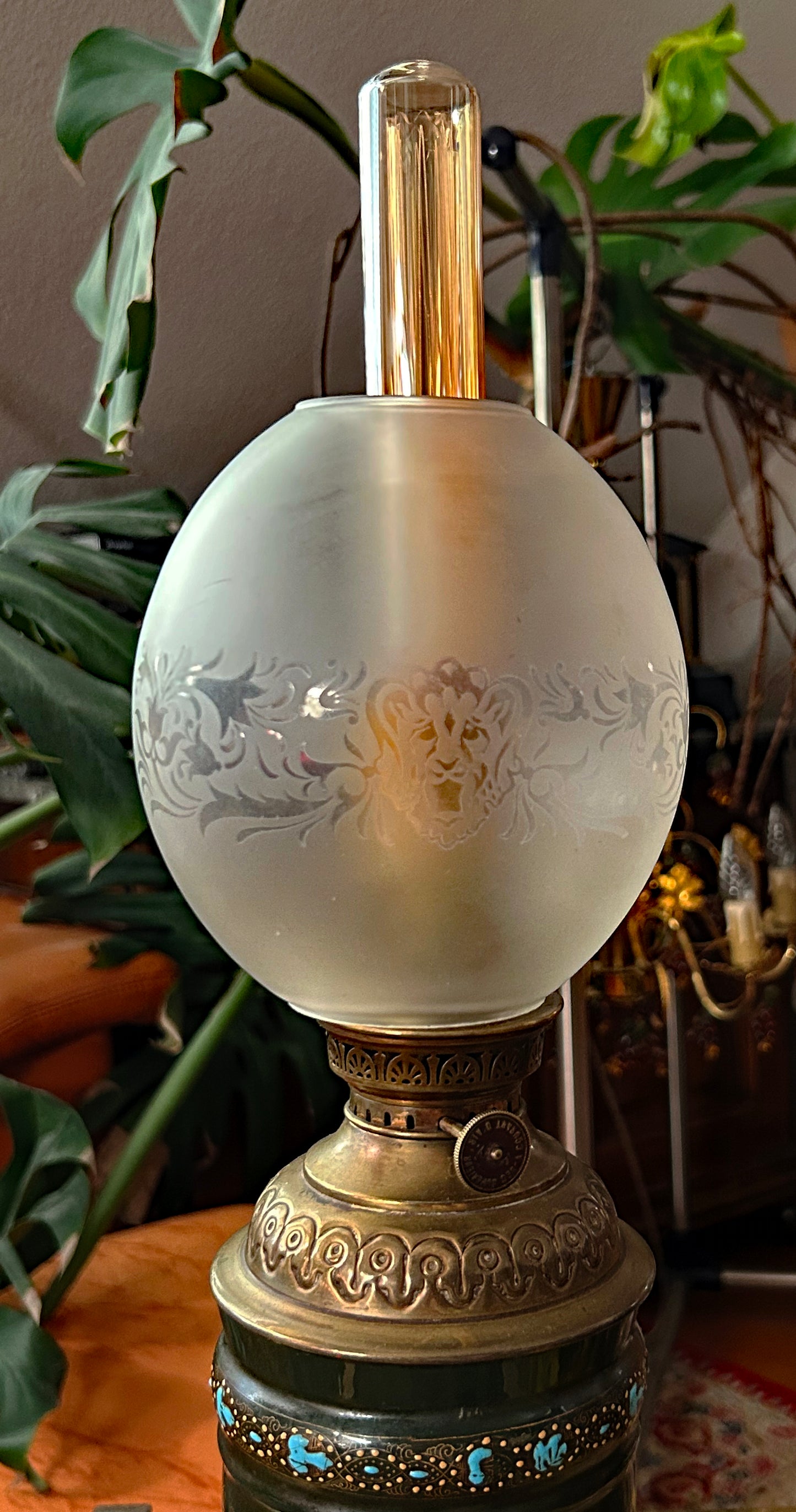 Close-up of frosted glass globe etched with lion mask and the brass burner mechanism
