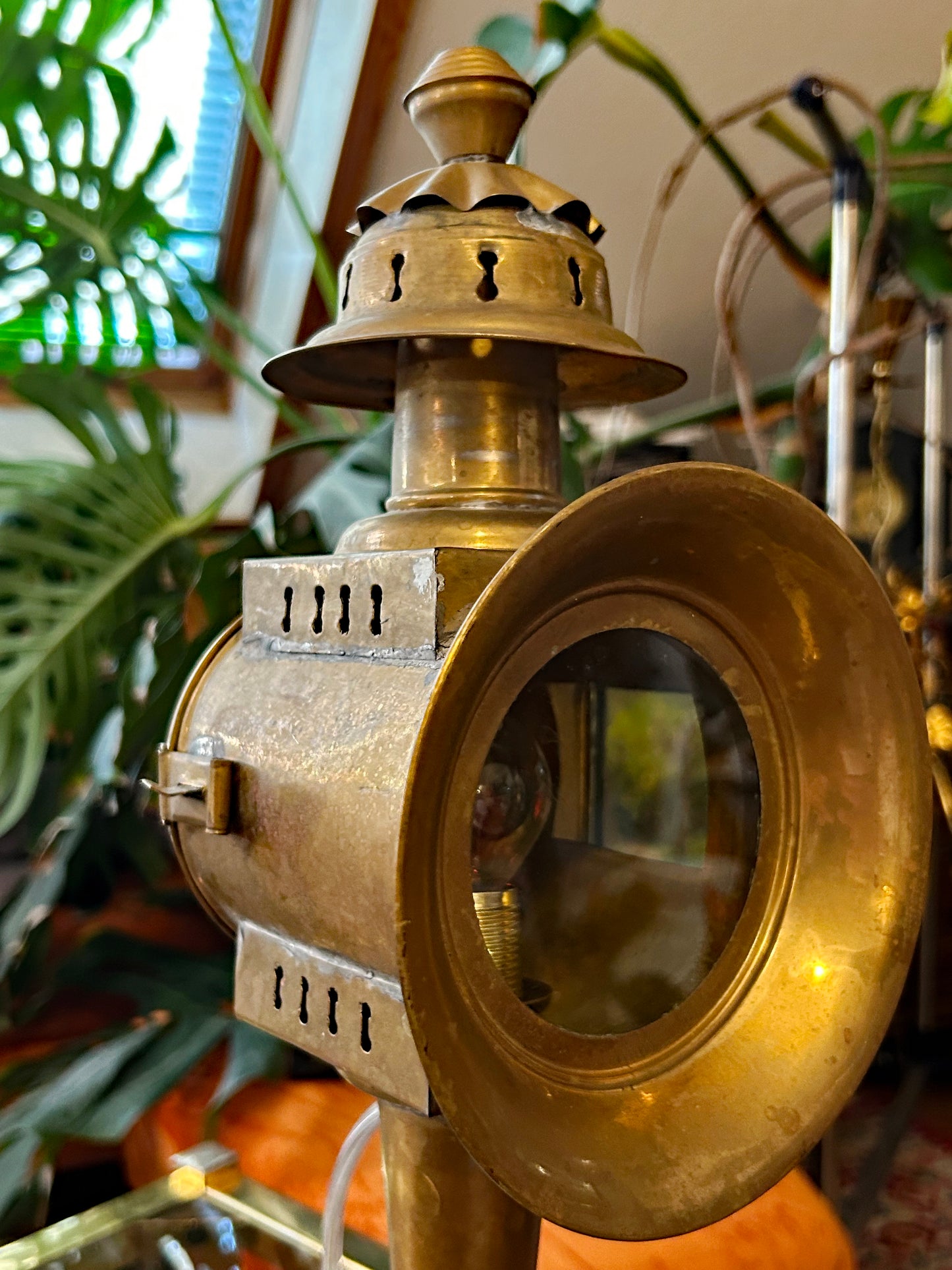 Sharp side view of brass carriage lamp showing vented body, hinged door and beveled lens