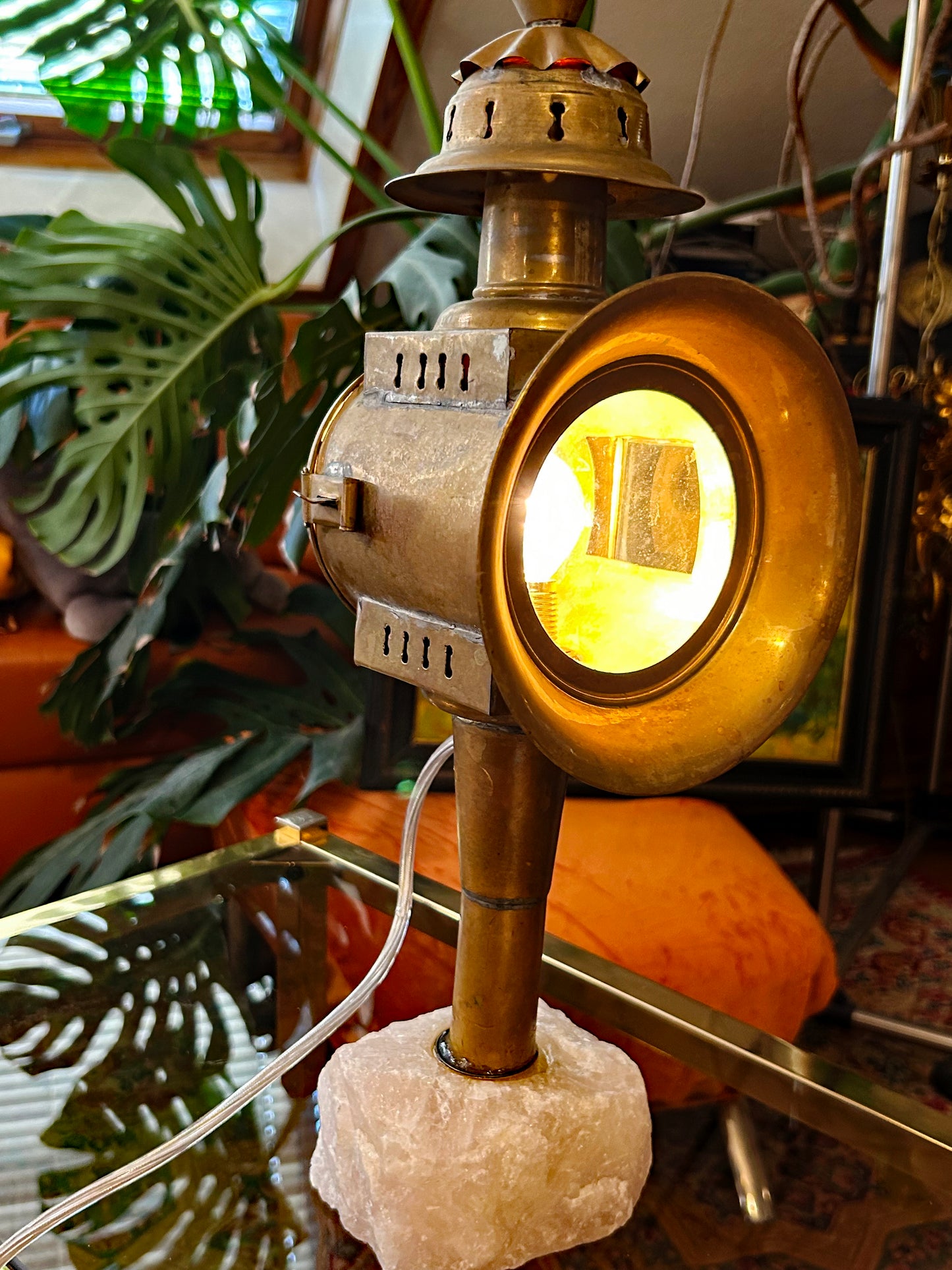 Antique coach lantern with glowing round beveled lens on raw rose quartz crystal base