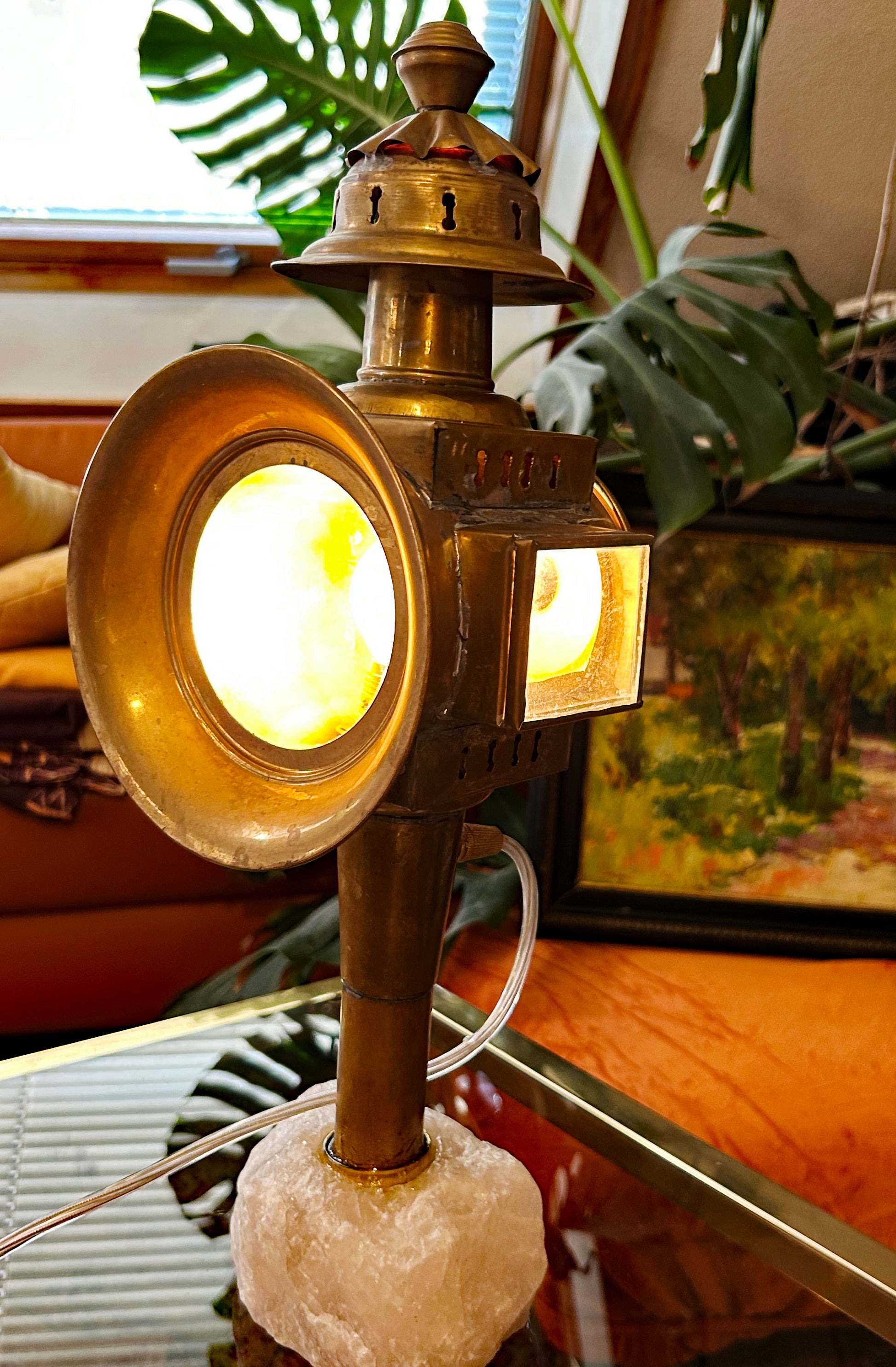 Electrified antique brass carriage lamp on rose quartz base, lit, three-quarter view