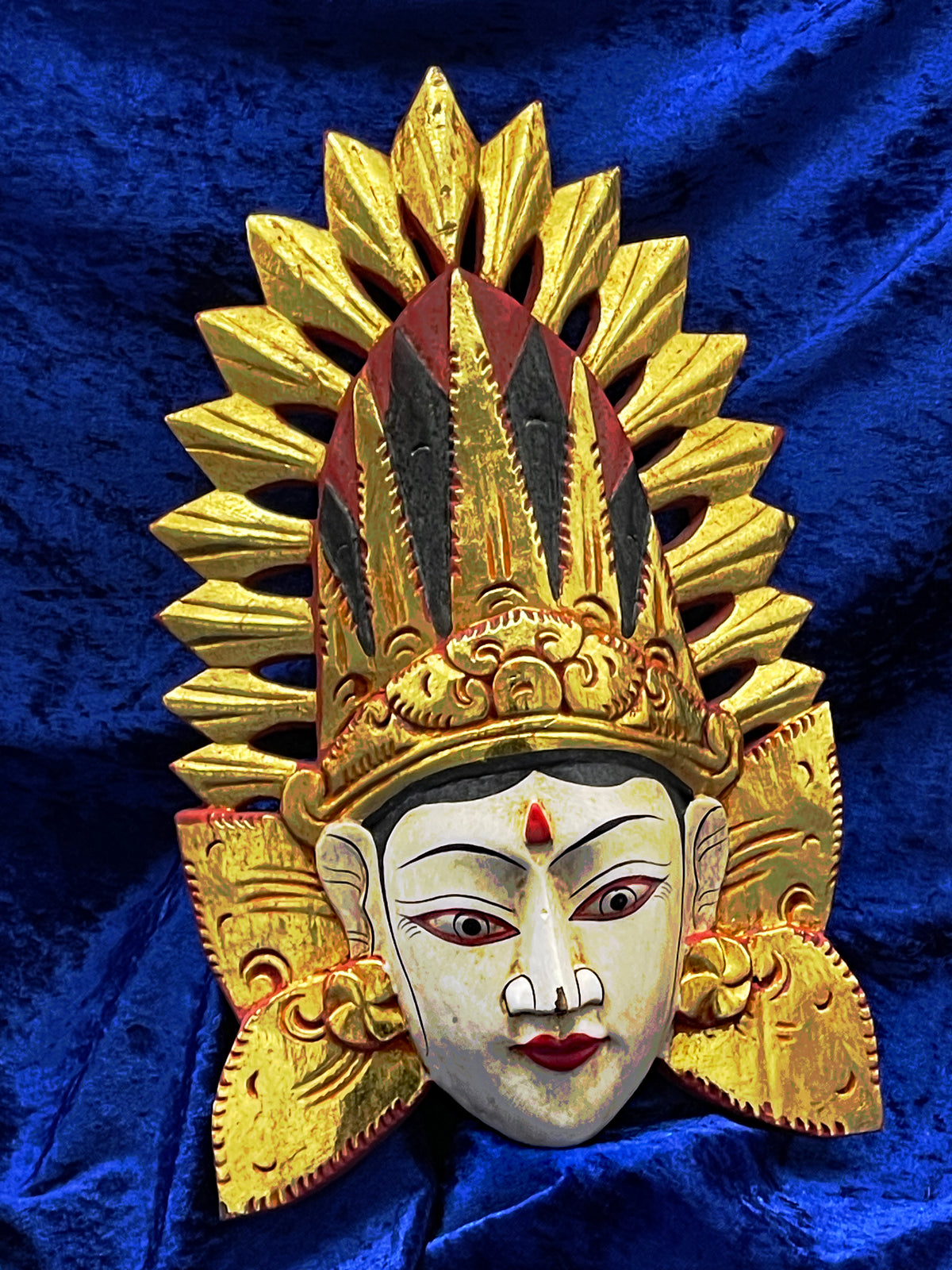 Balinese theatre wall mask, hand-carved gilded wood goddess with flaming crown, front view on blue velvet
