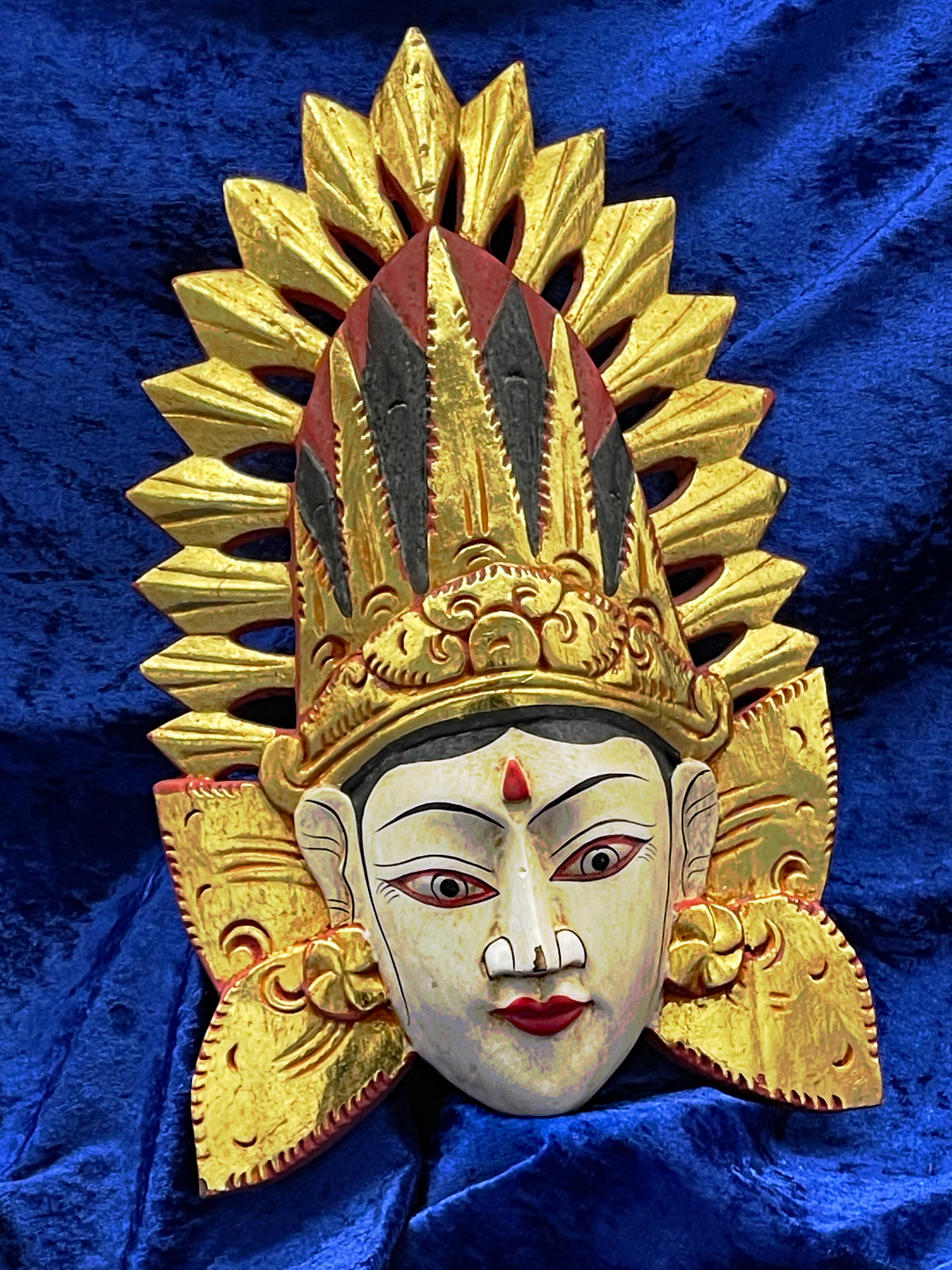 Hand-carved Balinese goddess wall mask with gilded crown and polychrome paint, angled front view