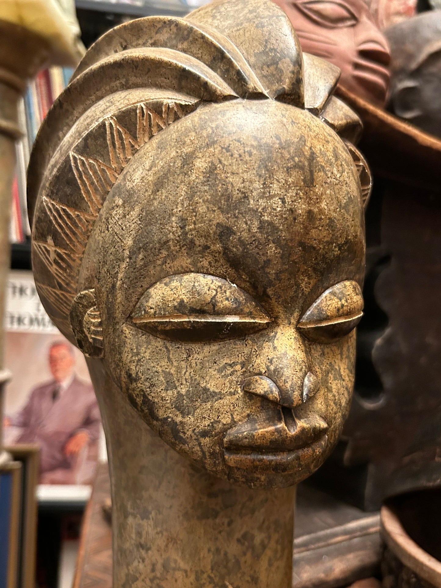 Detail of carved stone head showing weathered patina, eyes and scarification texture