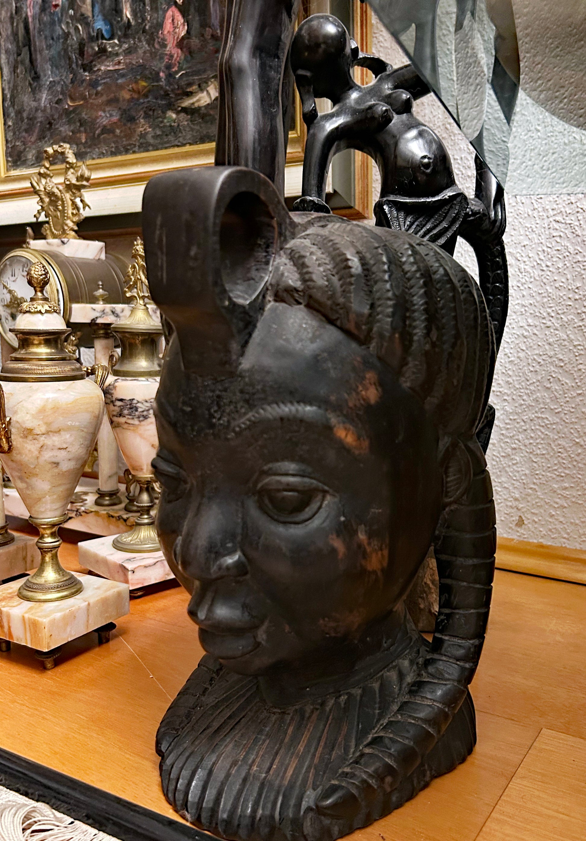 Left profile of large hand-carved ebony African bust showing plaited hair and topknot