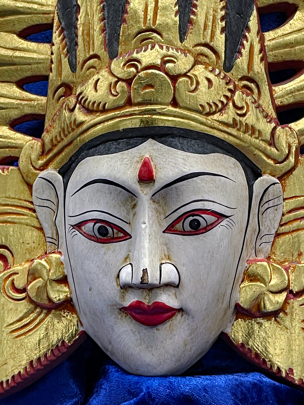 Detail of the gilded carved crown and forehead of the Balinese theatre wall mask