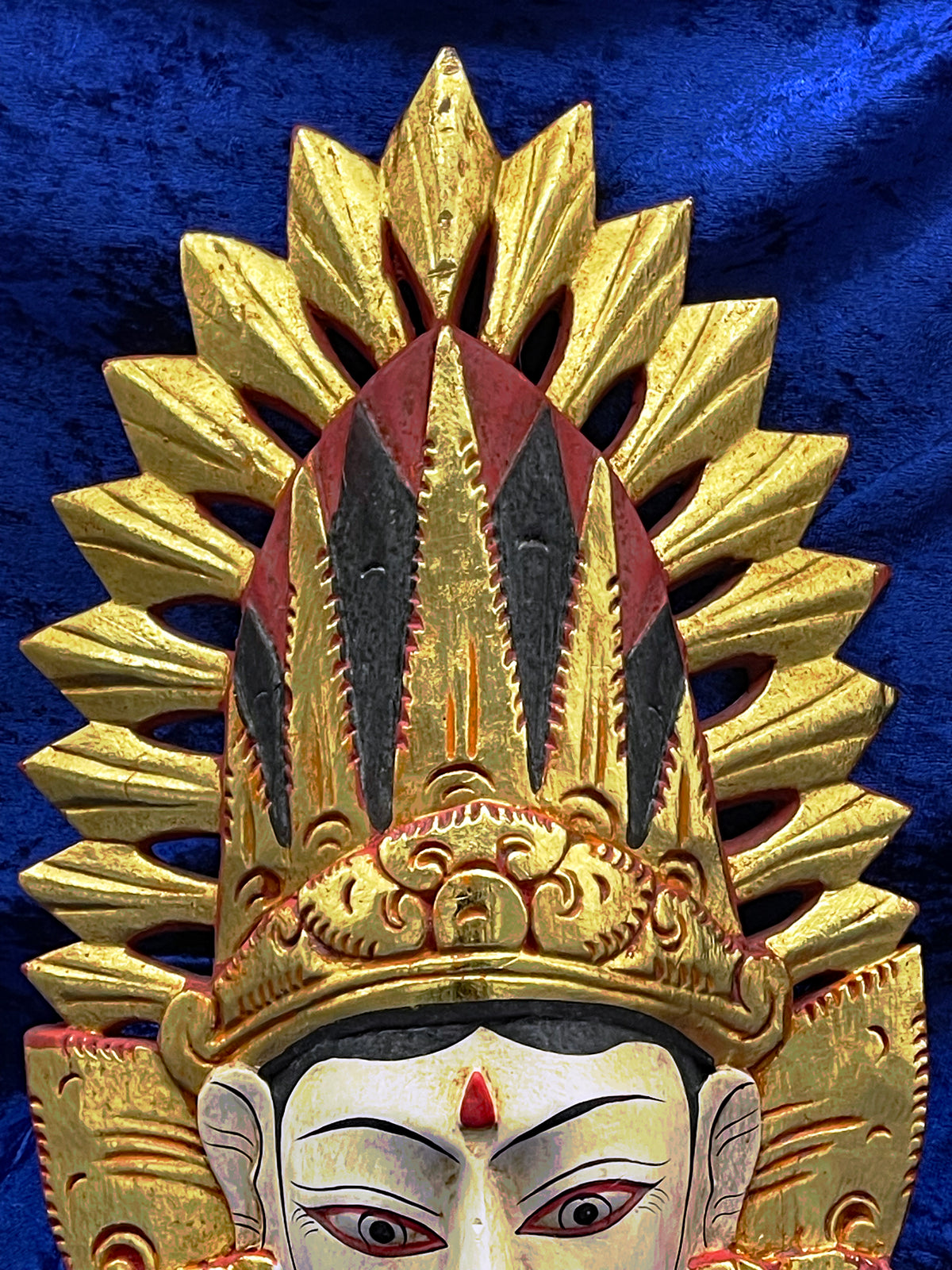 Top detail of the flaming gilded halo crown with red and charcoal accents of the Bali mask