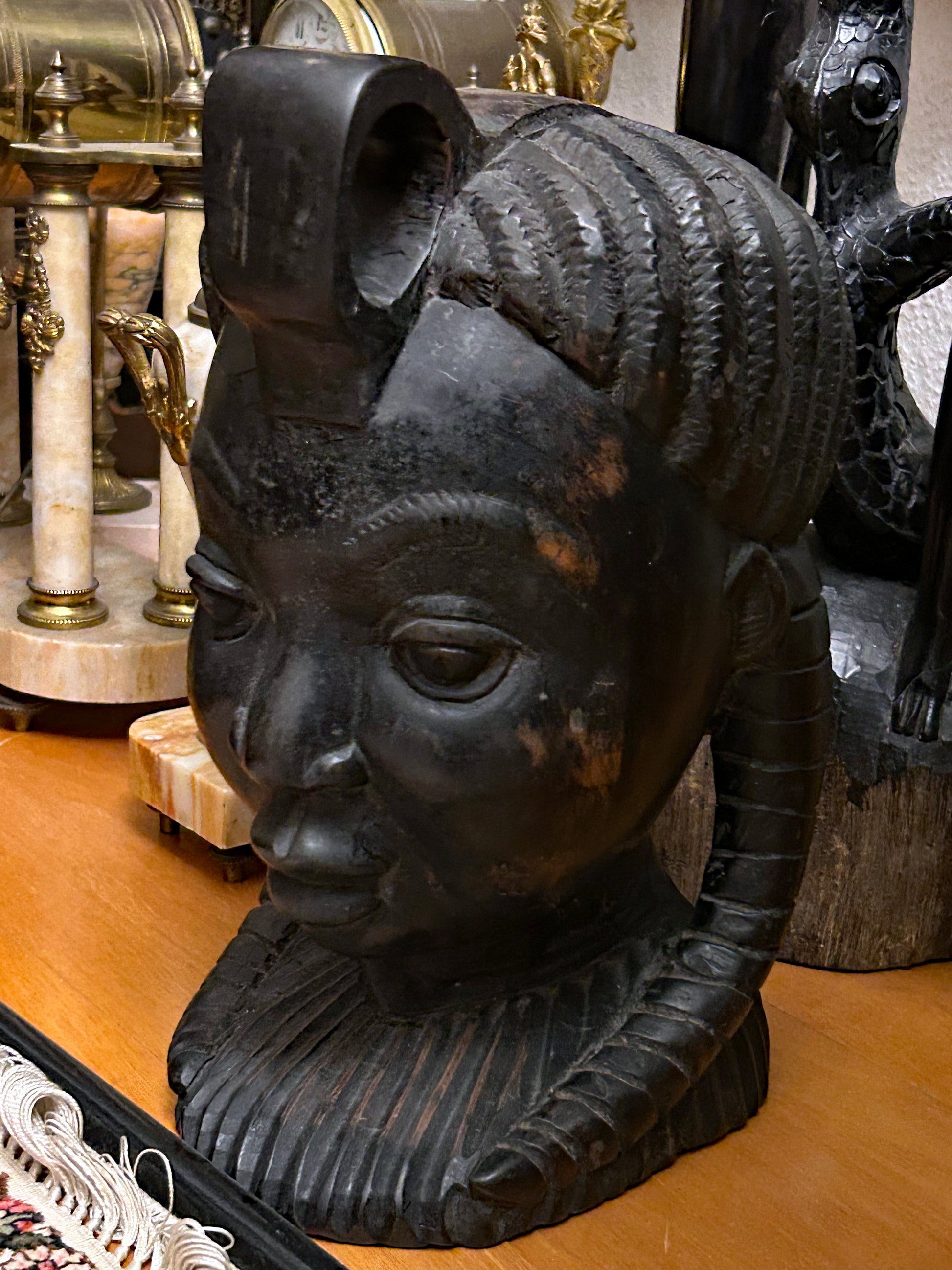 Front view of carved ebony African female head with serene features and braids