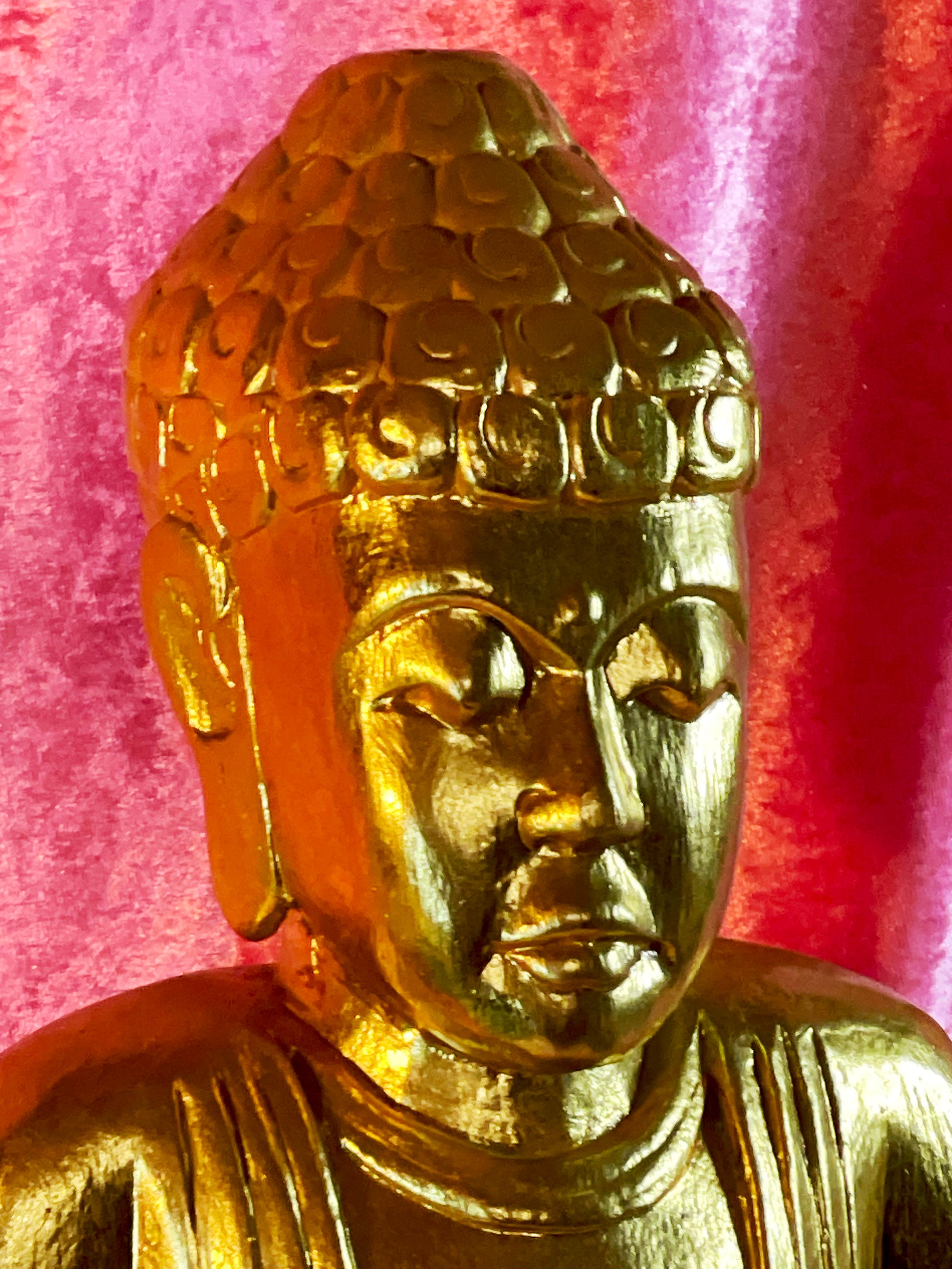 Close-up of gold Buddha face with downcast eyes and snail-curl ushnisha