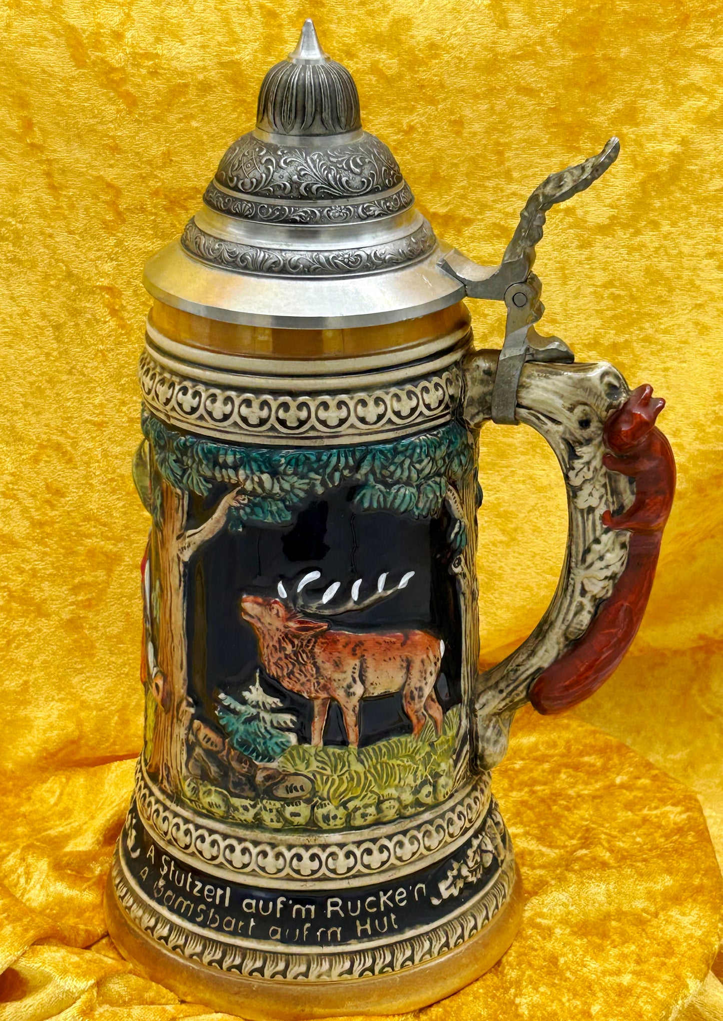 Three-quarter view of relief beer stein showing bellowing elk woodland panel and pewter lid