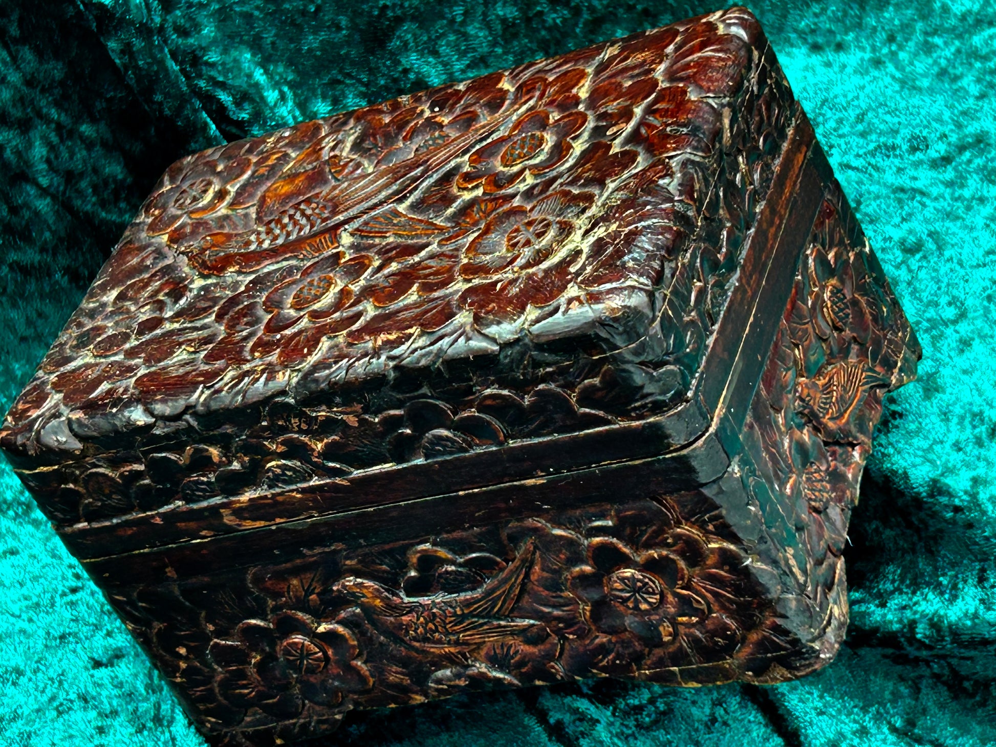 Three-quarter view of the carved box showing lid and decorated sides
