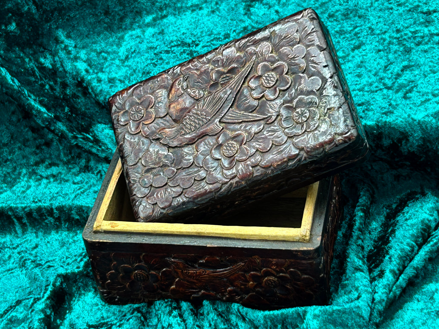 Carved wood box with lid lifted ajar revealing the fitted rim