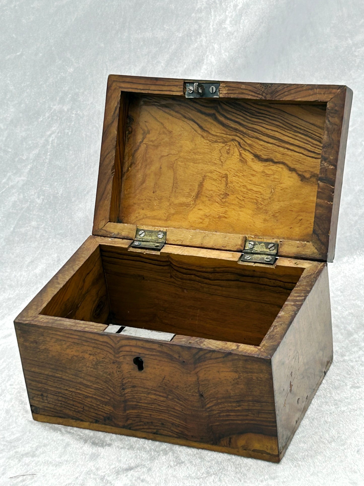 Interior of antique olive wood box open, showing brass hinges and grained wood