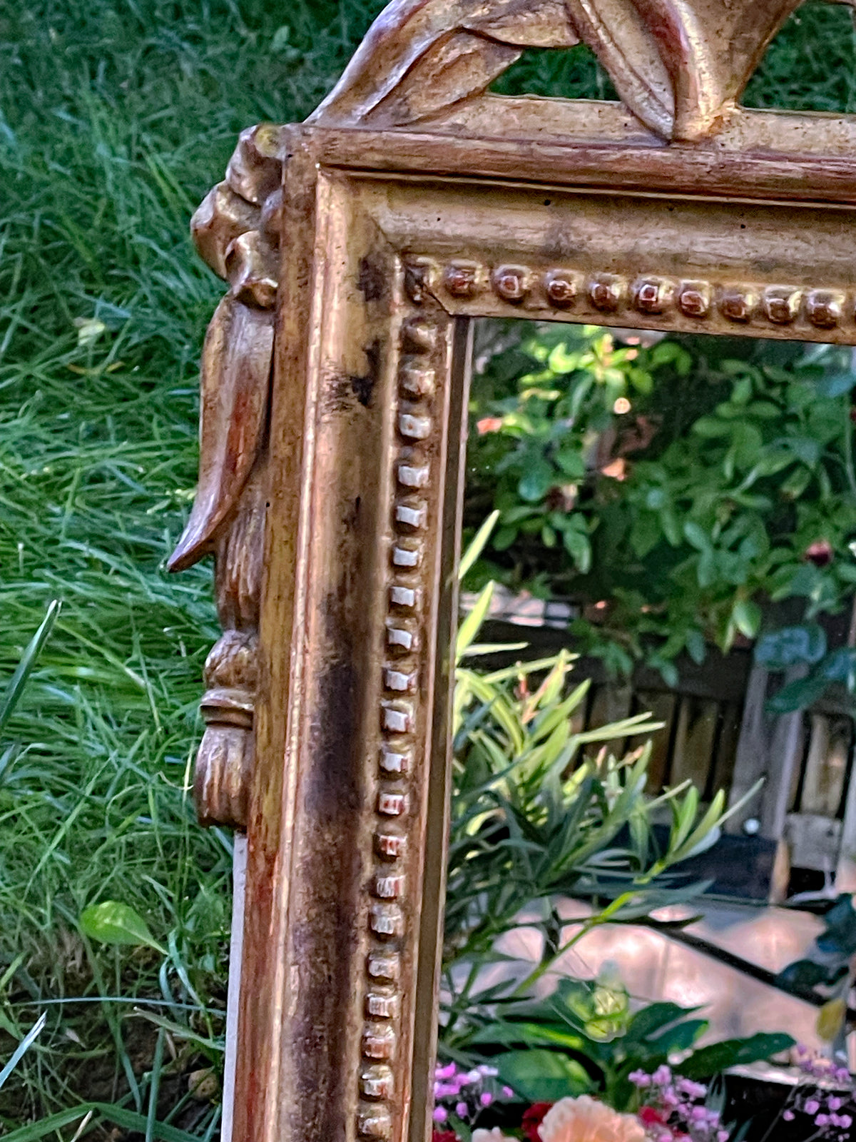 Pearl bead frieze and carved tassel at the left corner of the gilt mirror frame