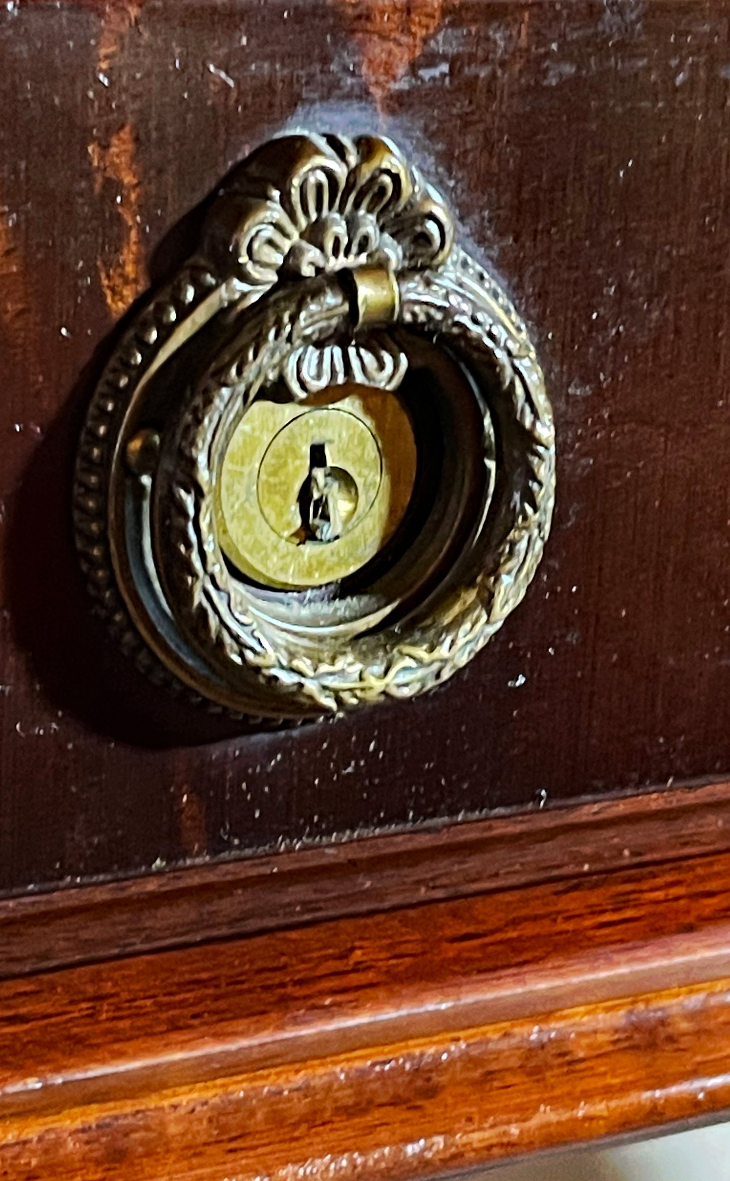 Brass drawer escutcheon and ring-pull with engraved monogram on mahogany frieze drawer