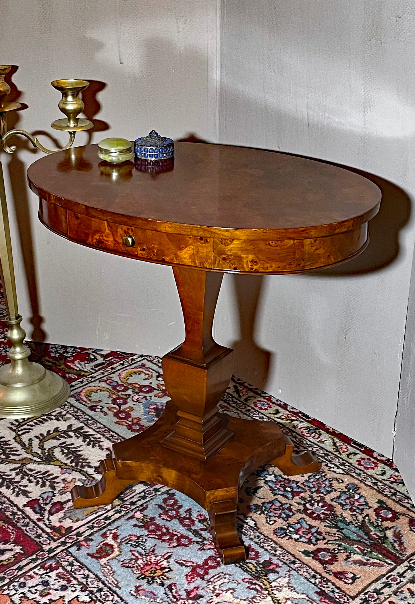 Burl wood oval side table shown three-quarter view in a styled interior