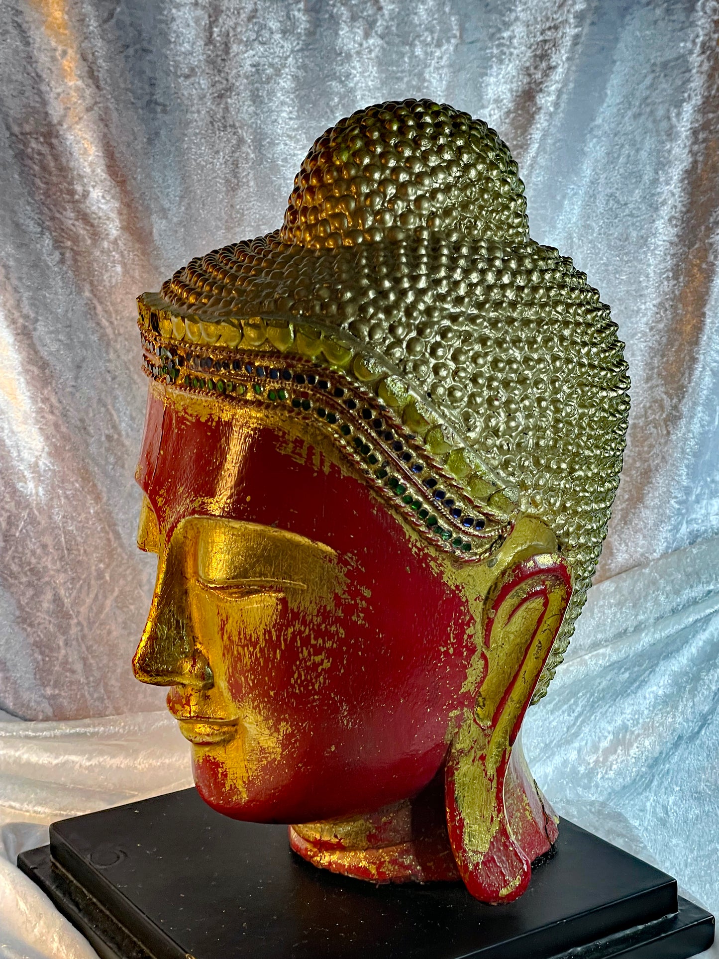 Profile of the gilded Buddha head showing the curled ushnisha topknot and elongated ear
