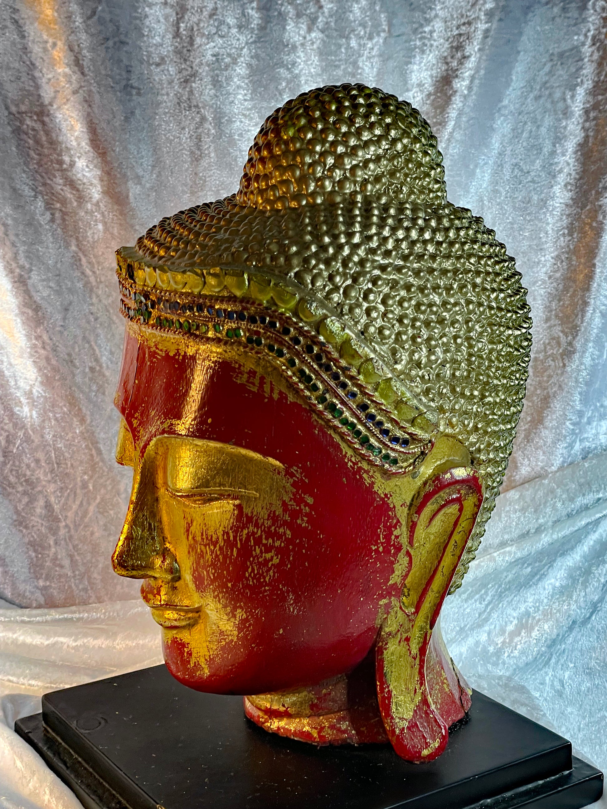 Profile of the gilded Buddha head showing the curled ushnisha topknot and elongated ear