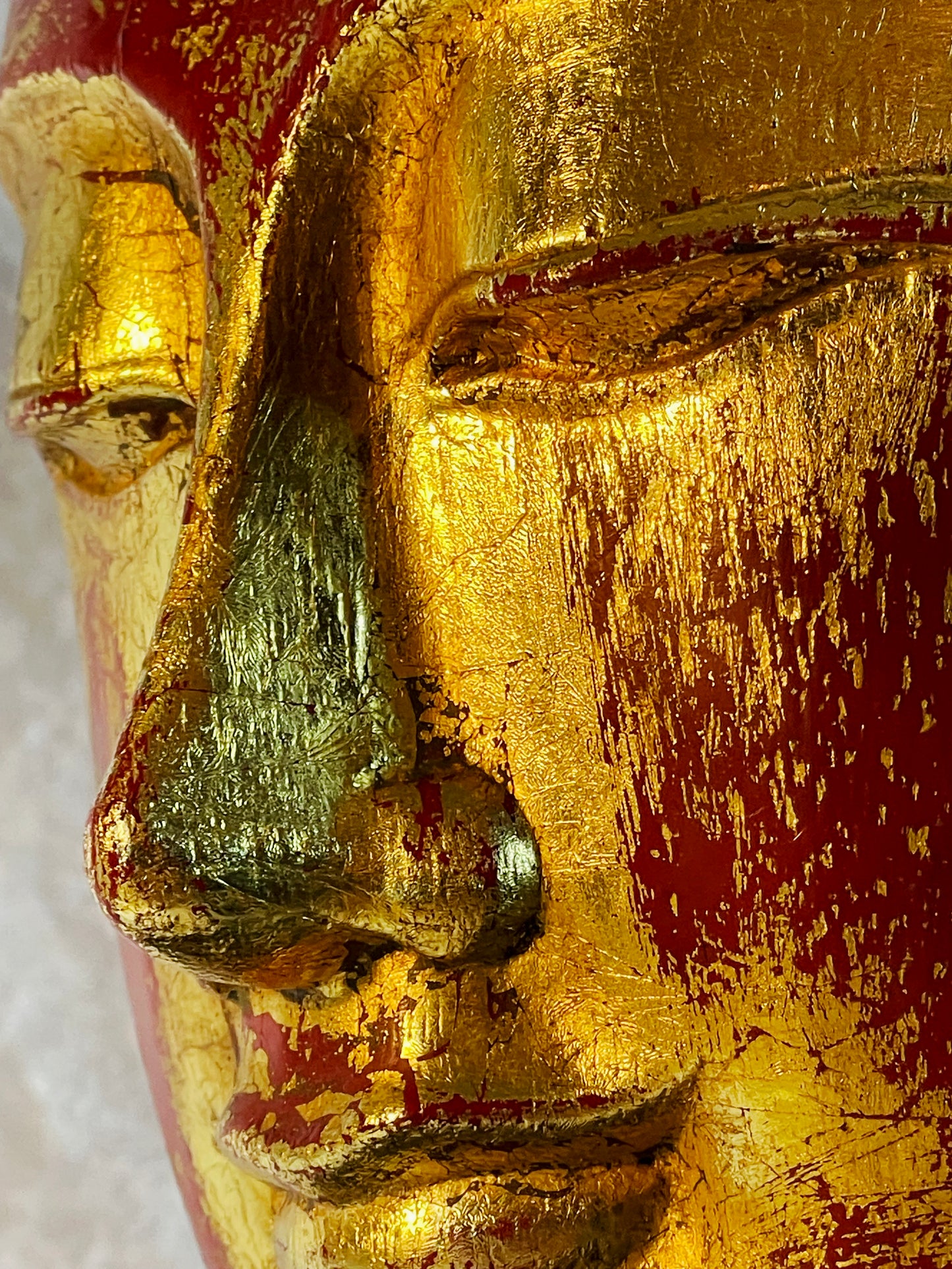 Macro detail of the gilded nose and downcast eyes of the Buddha head