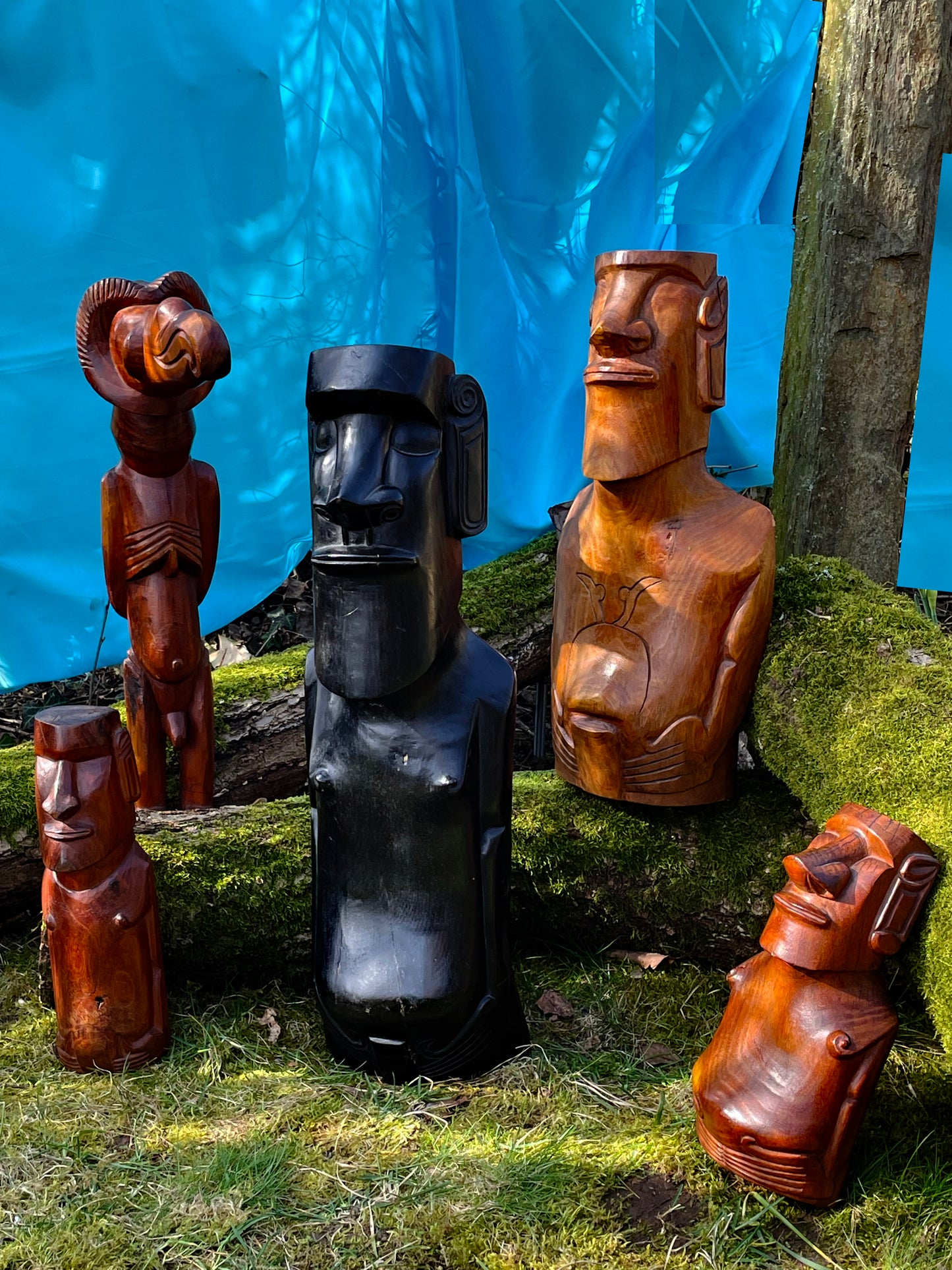 Collection of five carved Easter Island Rapa Nui Moai figures with Birdman on a mossy bank