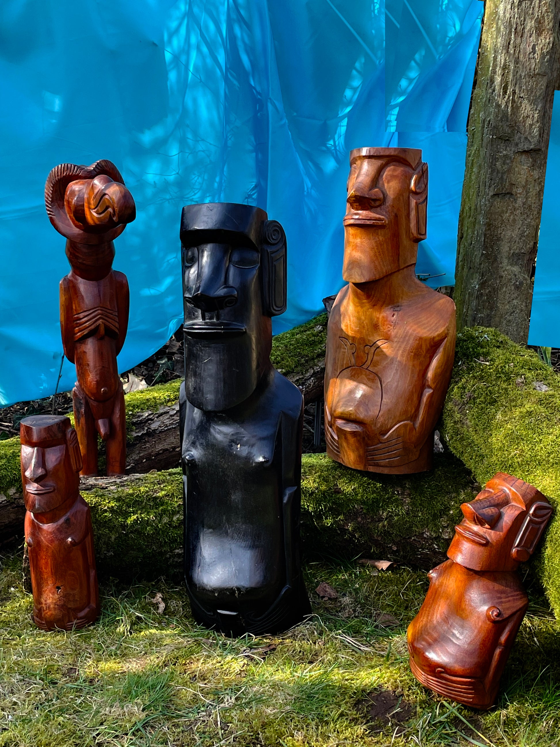 Collection of five carved Easter Island Rapa Nui Moai figures with Birdman on a mossy bank