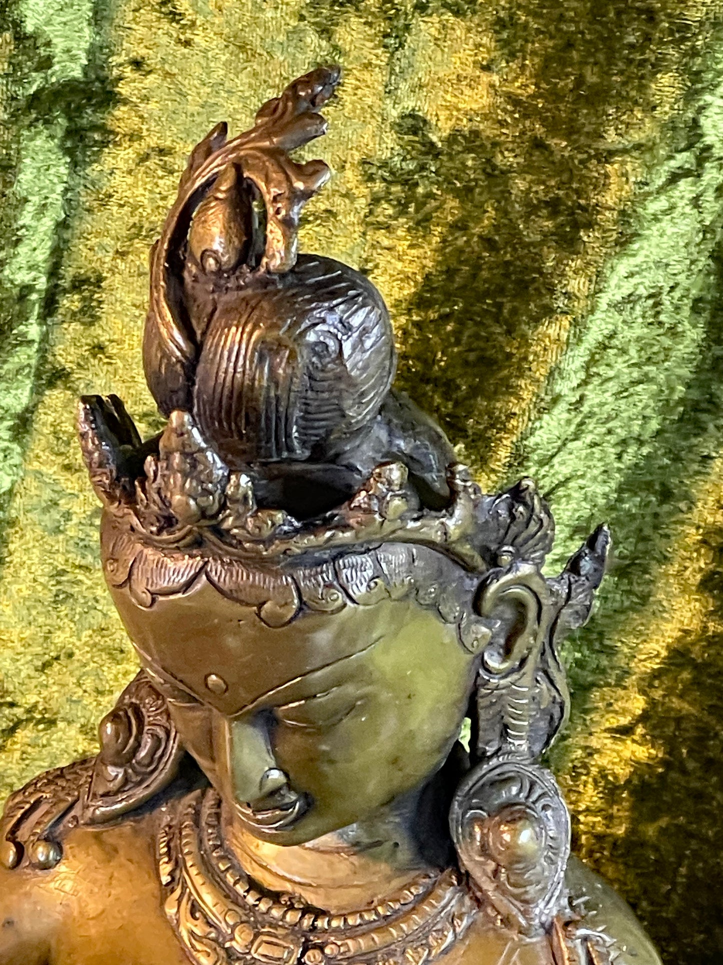 Close up of Green Tara's crowned head and high chignon with foliate ornaments