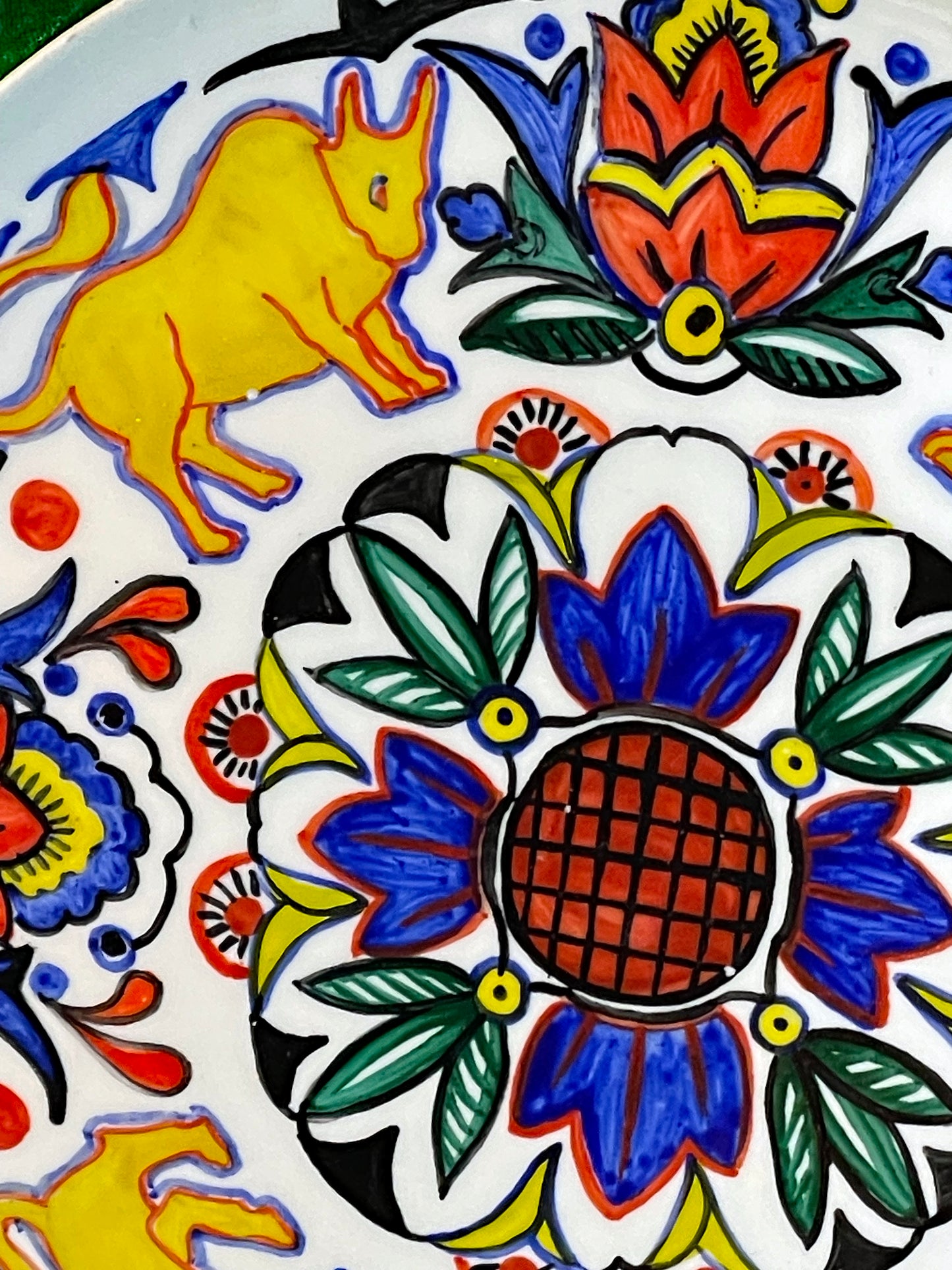 Angled view of the plate showing a golden ox and the central blue and terracotta medallion