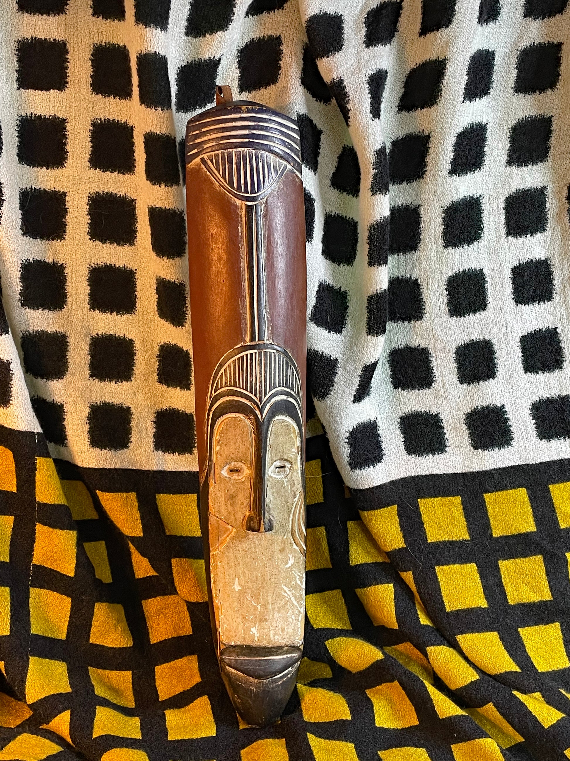 Slender hand-carved African Fang-style wood mask with whitened elongated face, full front view