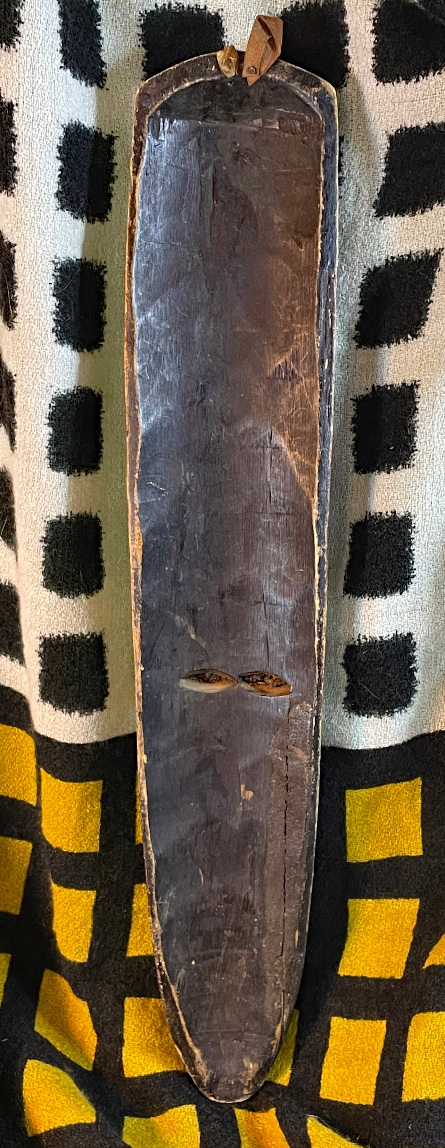 Angled view of the African wood mask highlighting its narrow silhouette