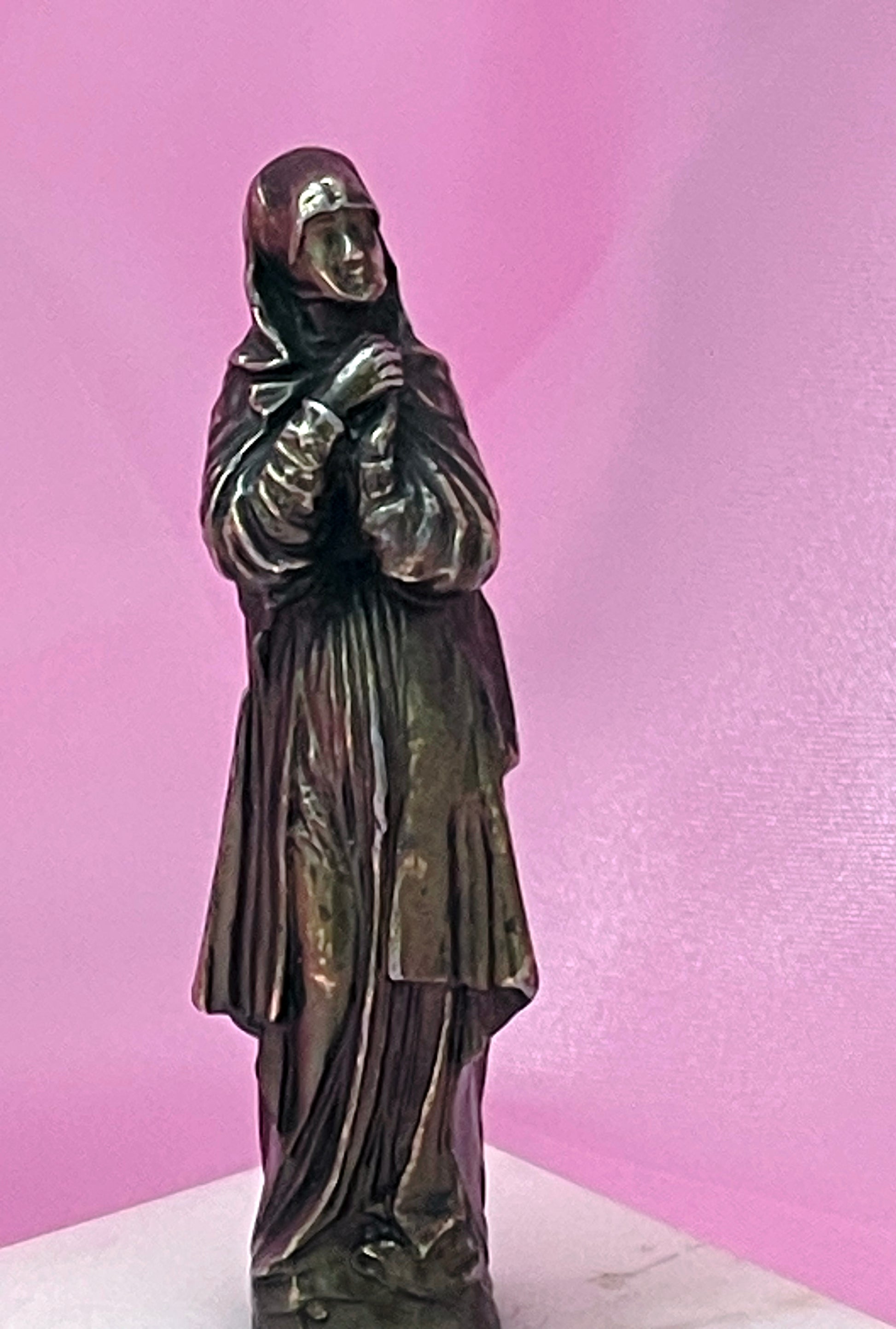 Bronze Virgin Mary sculpture on marble plinth, detail