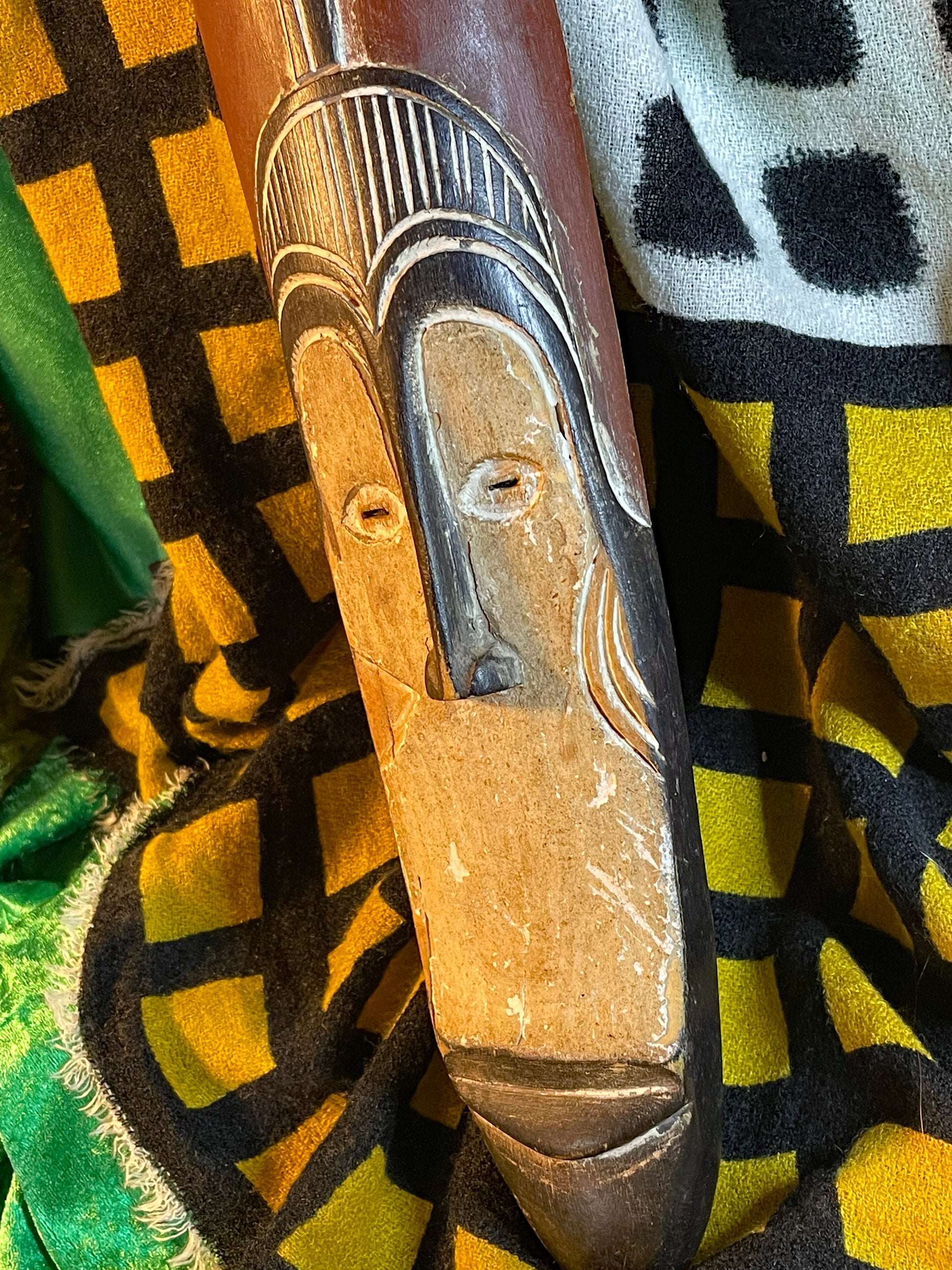 Hand-carved African mask at three-quarter angle showing slim elongated form