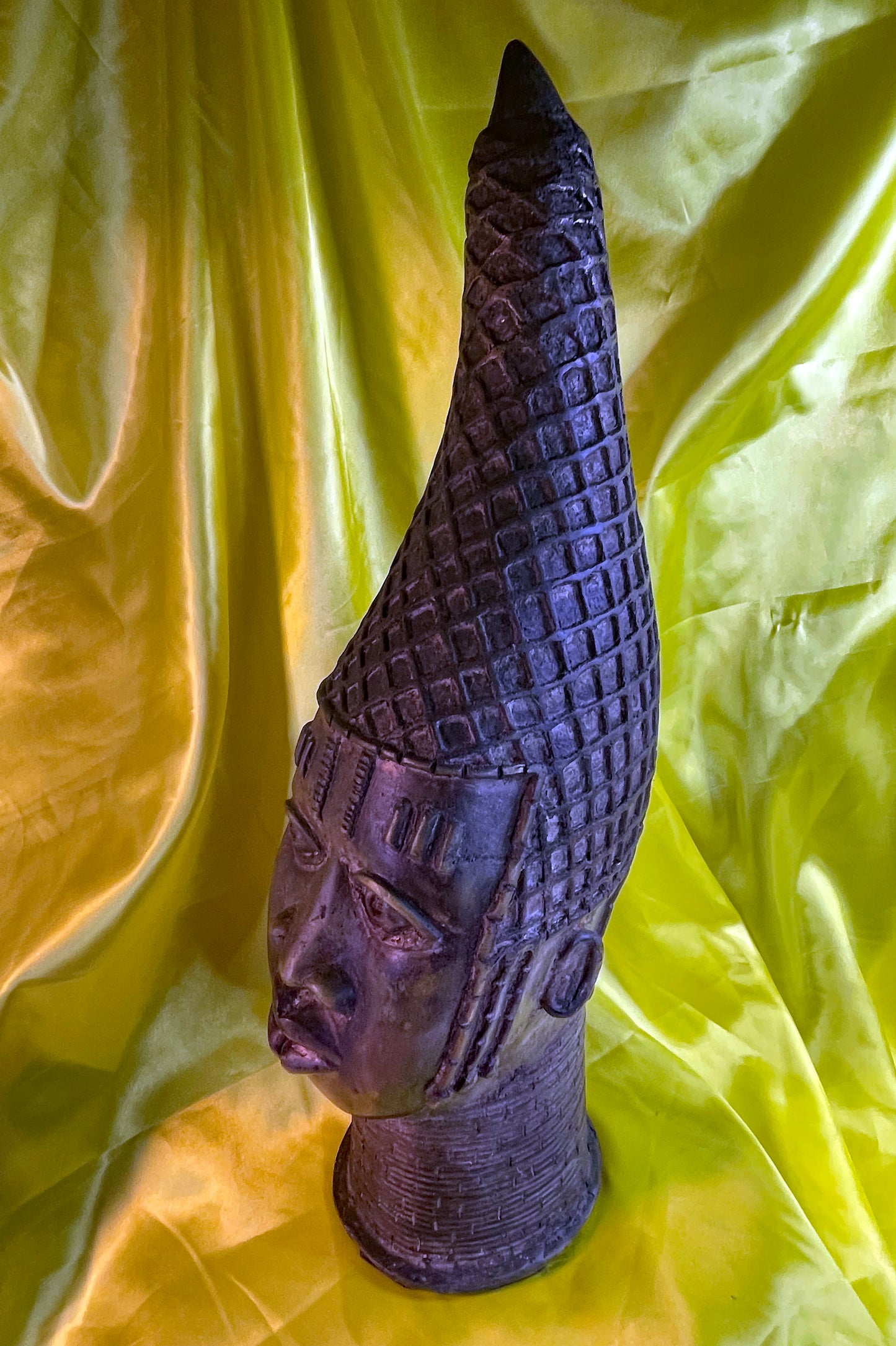Full profile of the Benin bronze Queen Mother head showing its dramatic tall crown