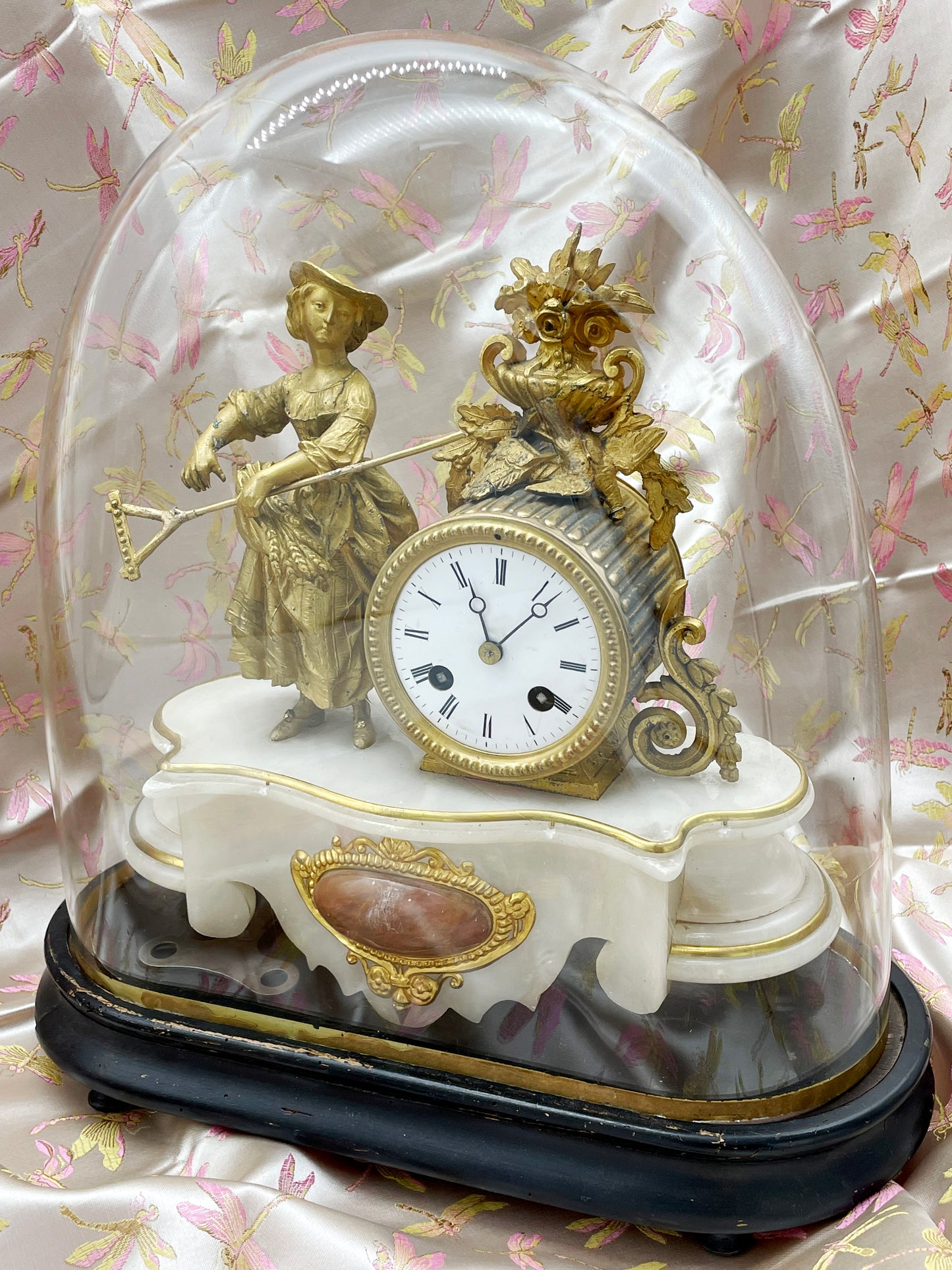 Full view of the 19th-century French pendule beneath its glass dome on an ebonised oval plinth