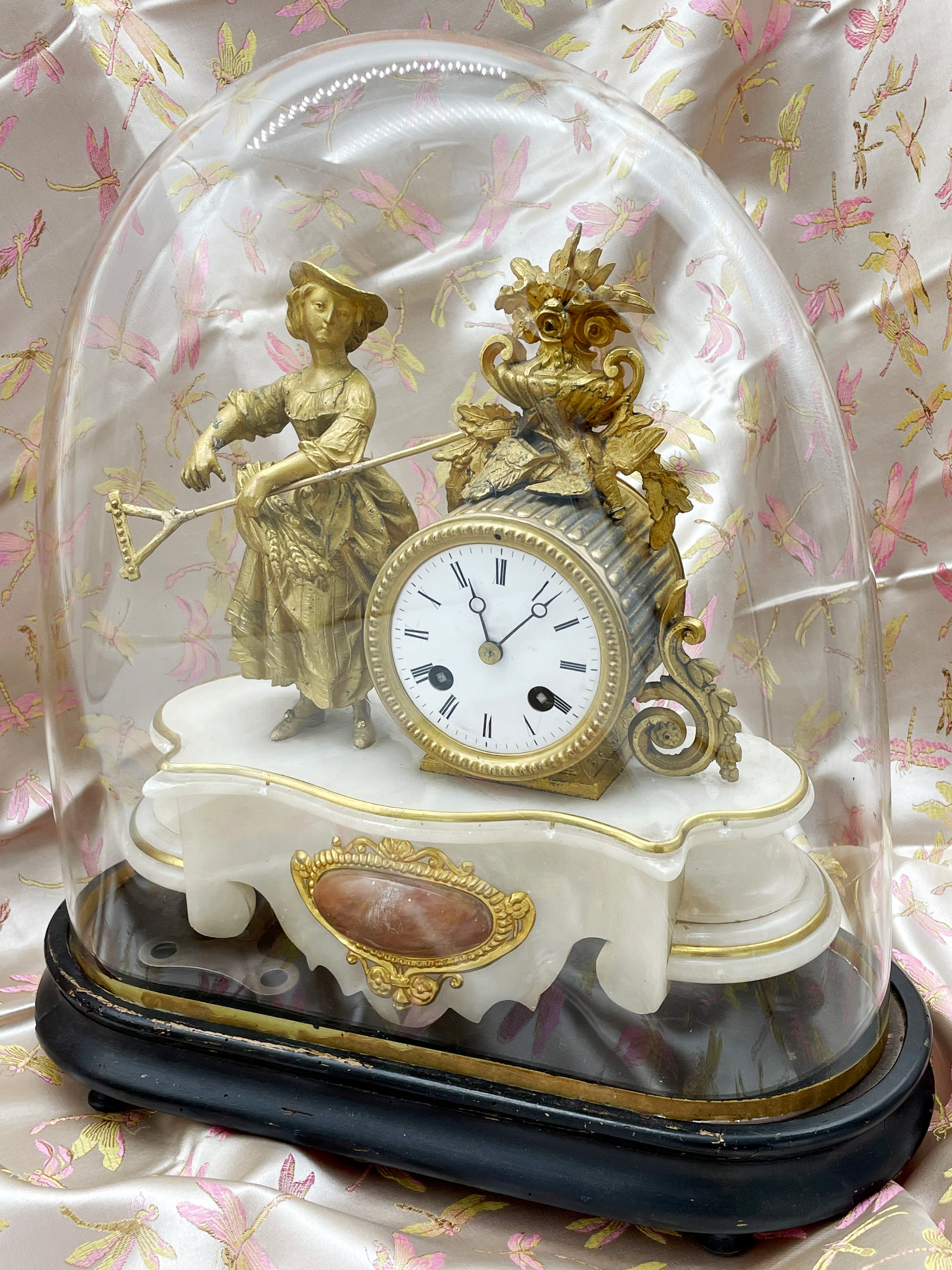 Full view of the 19th-century French pendule beneath its glass dome on an ebonised oval plinth