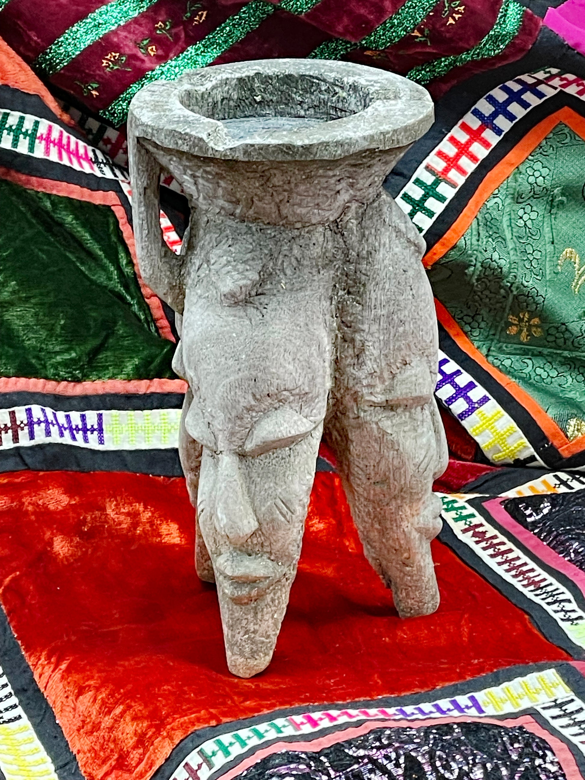 Side view of hand-carved ritual cult object showing anthropomorphic carved faces