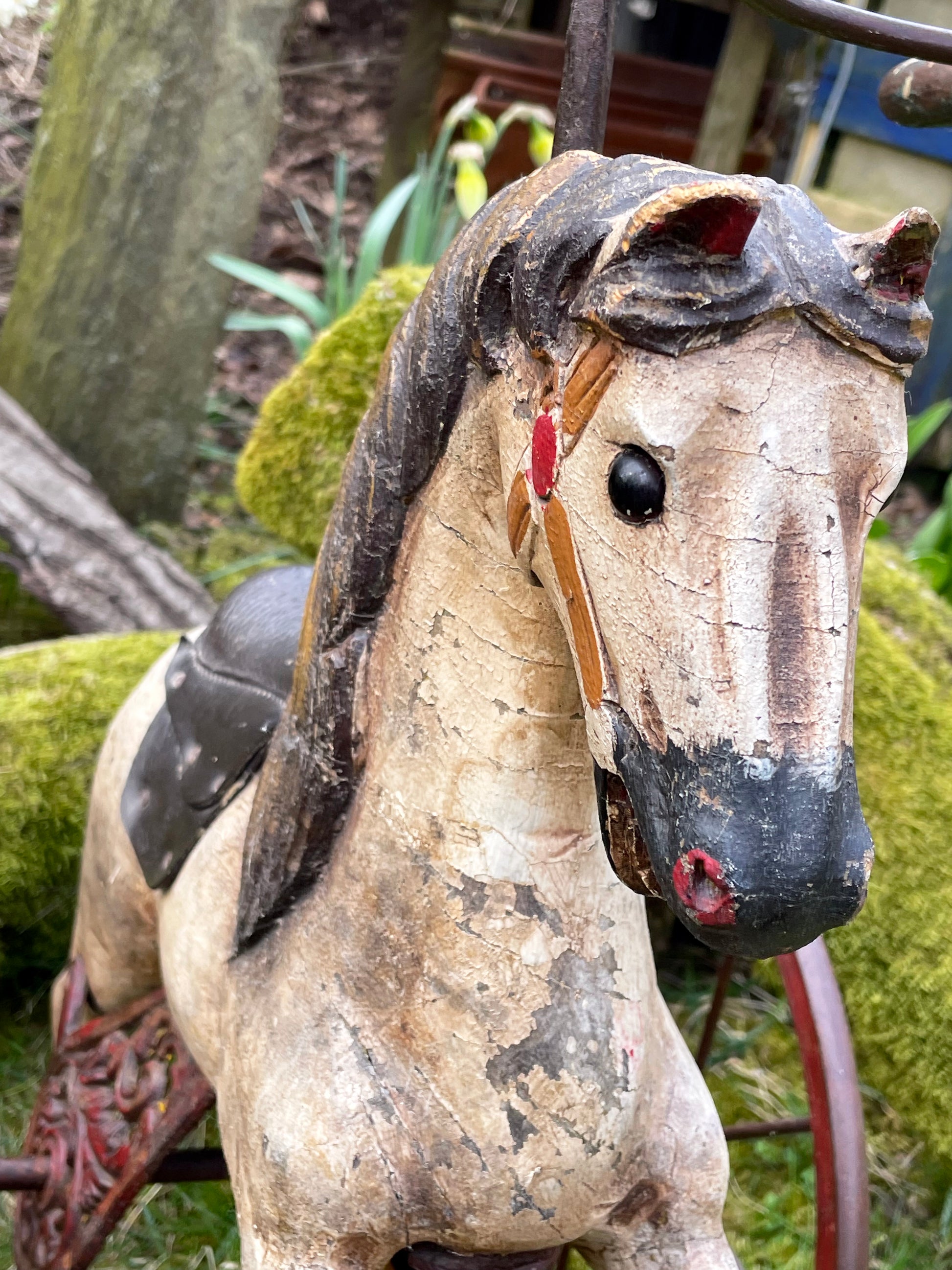 Close-up of the horse's hand-carved head, painted eye, red bridle and crackled dapple grey patina