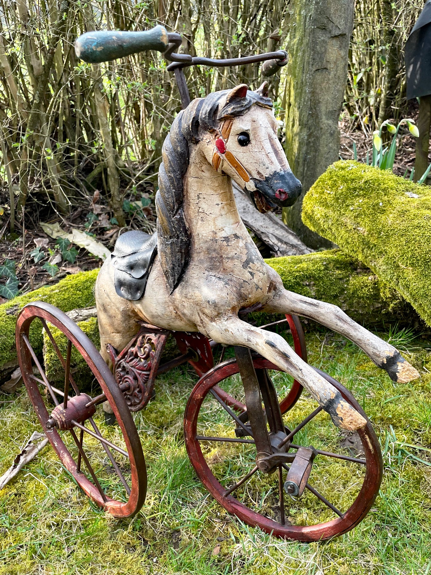 Three quarter front view of the hand-painted dapple grey wooden horse tricycle with leather saddle and bridle