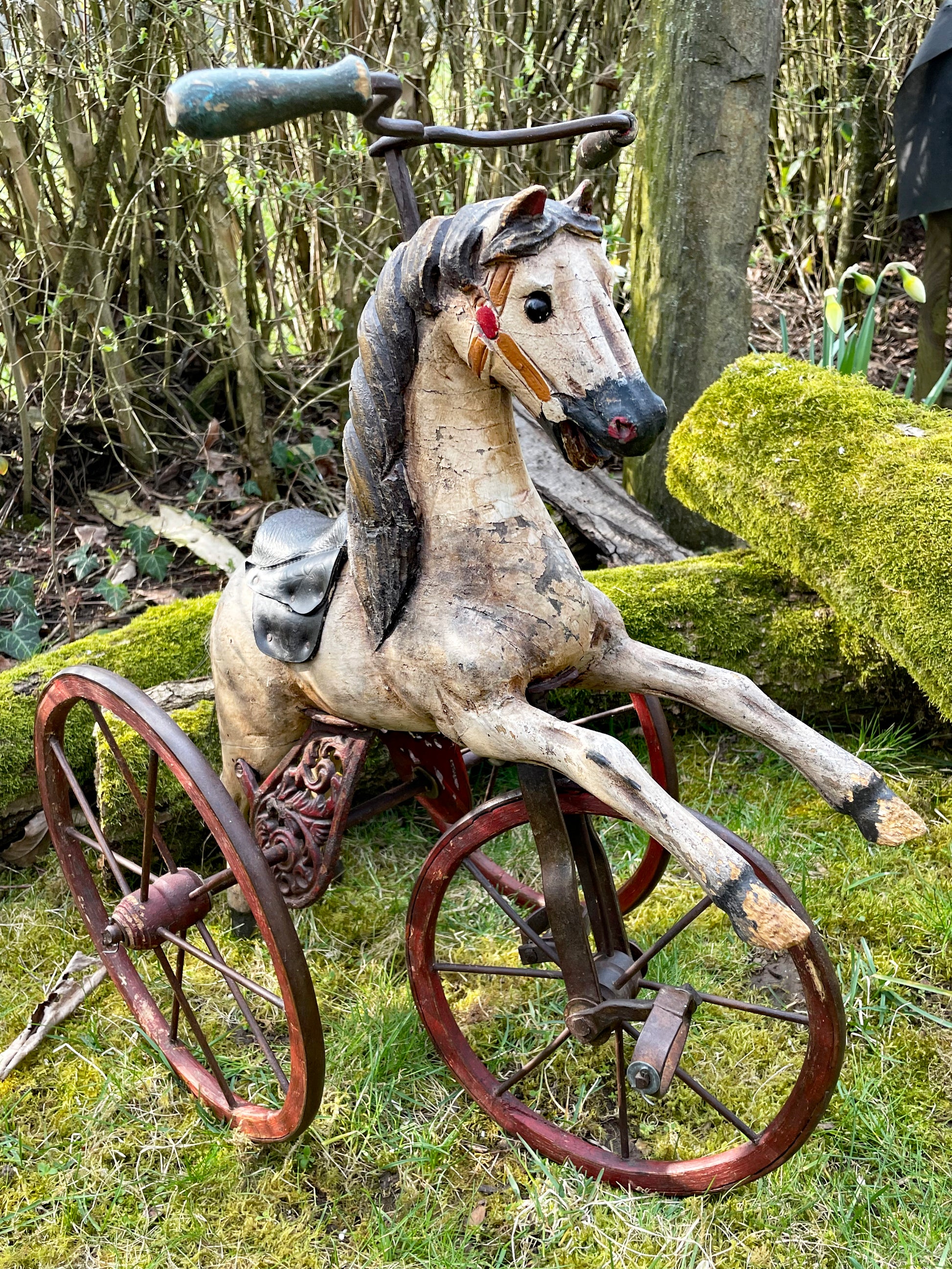 Three quarter front view of the hand-painted dapple grey wooden horse tricycle with leather saddle and bridle