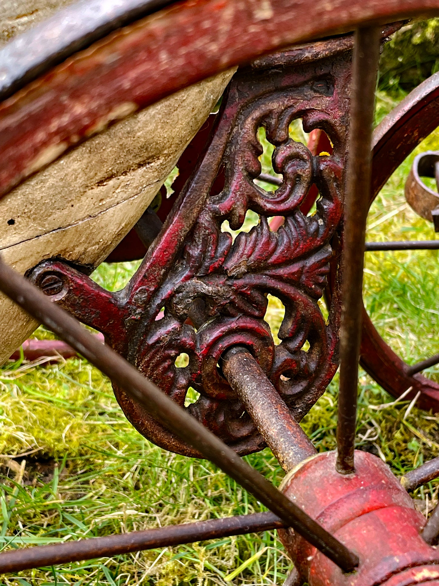 Close-up of the ornate cast iron pedal crank with foliate scrollwork, painted red