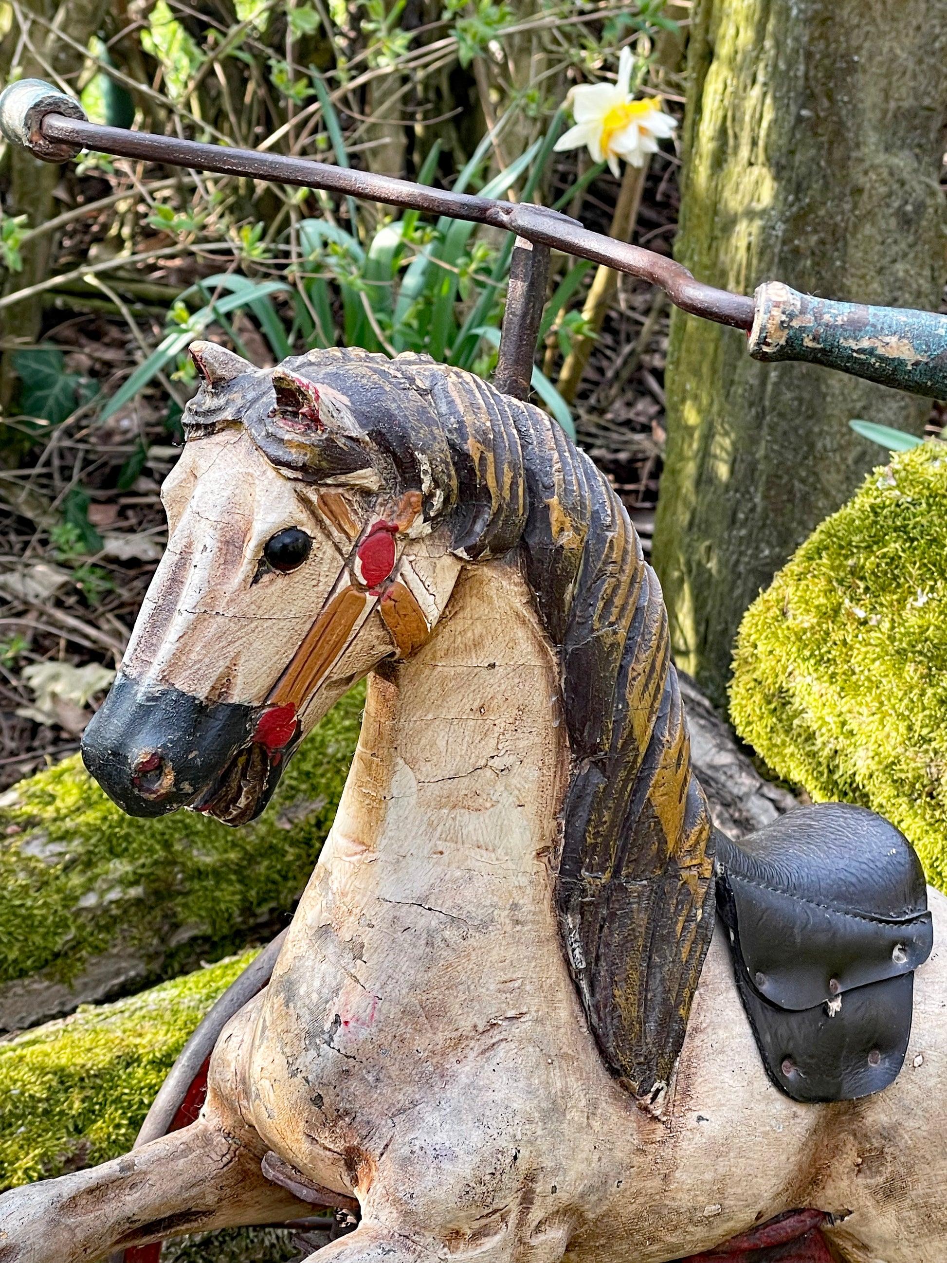 Detail of the carved charcoal mane, leather saddle and turned wooden handlebar of the velocipede
