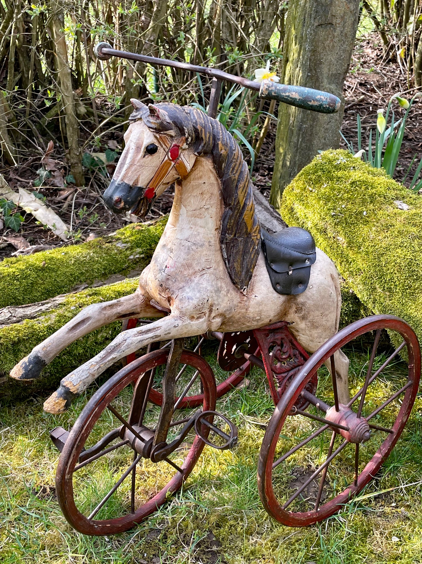 Three quarter view of the antique horse velocipede showing the carved mane, leather saddle and ornate cast iron crank