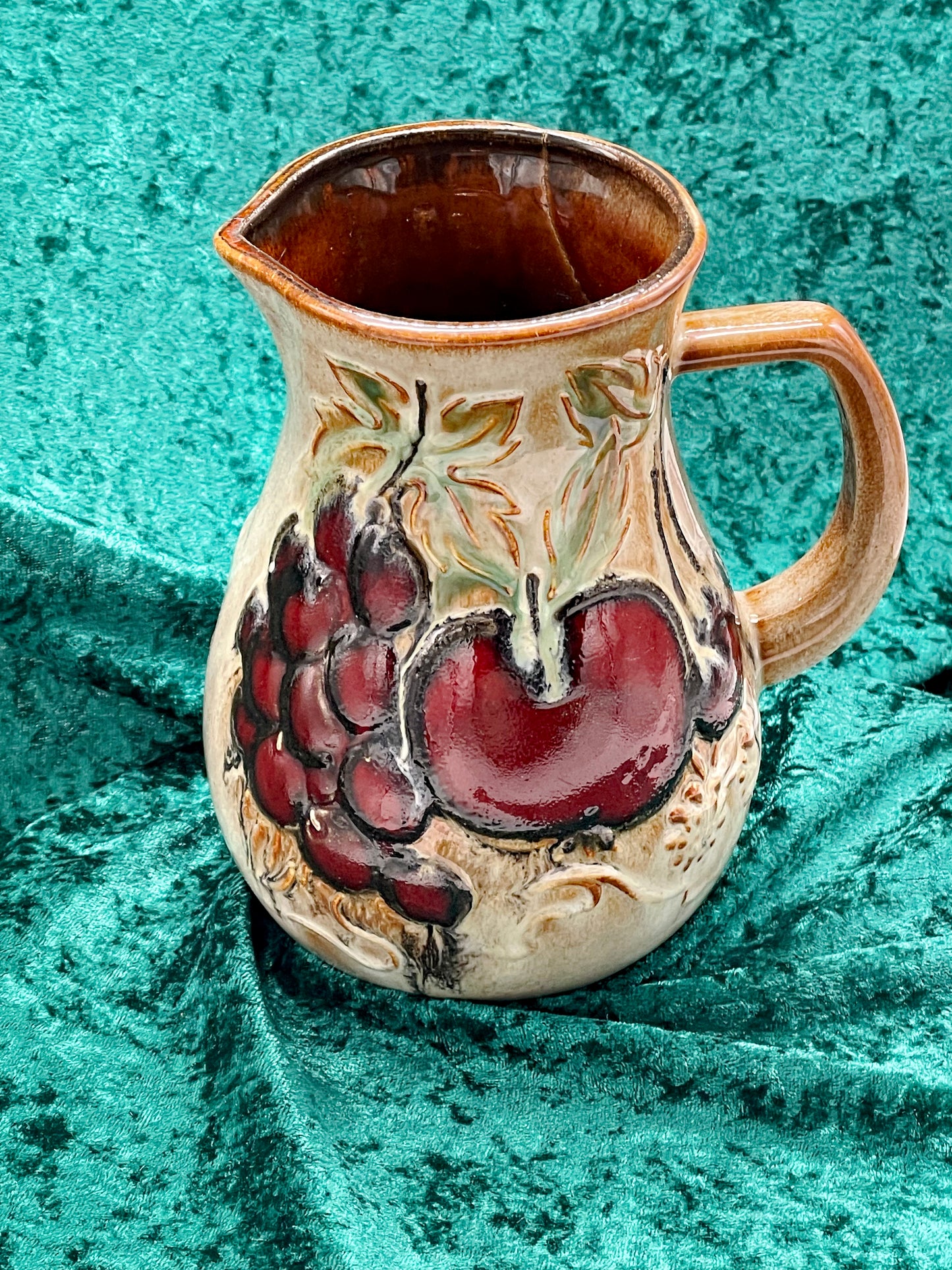 Hand-painted fruit relief jug with chestnut-brown handle, three-quarter view