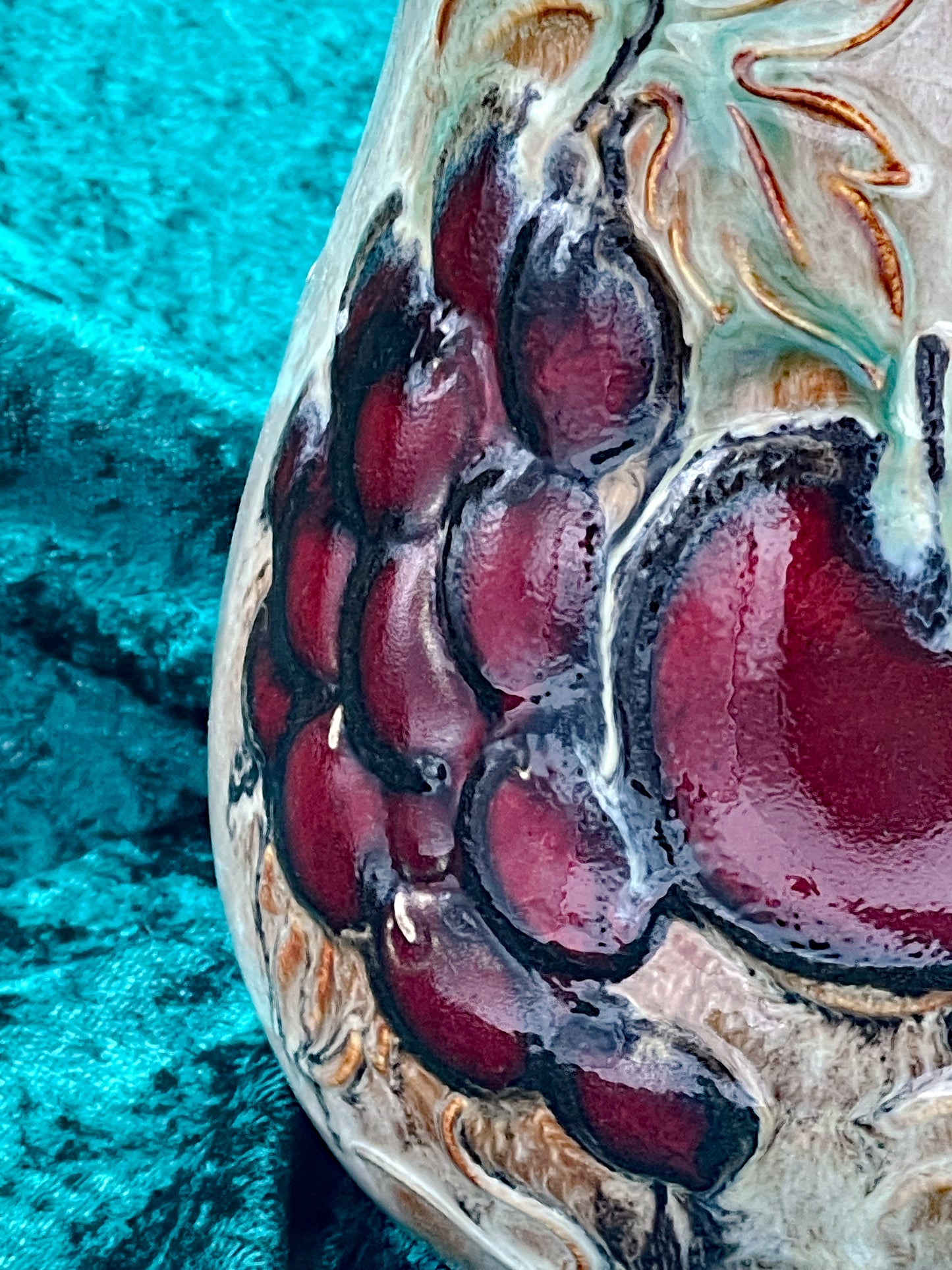 Macro detail of the hand-painted grape cluster on the ceramic jug