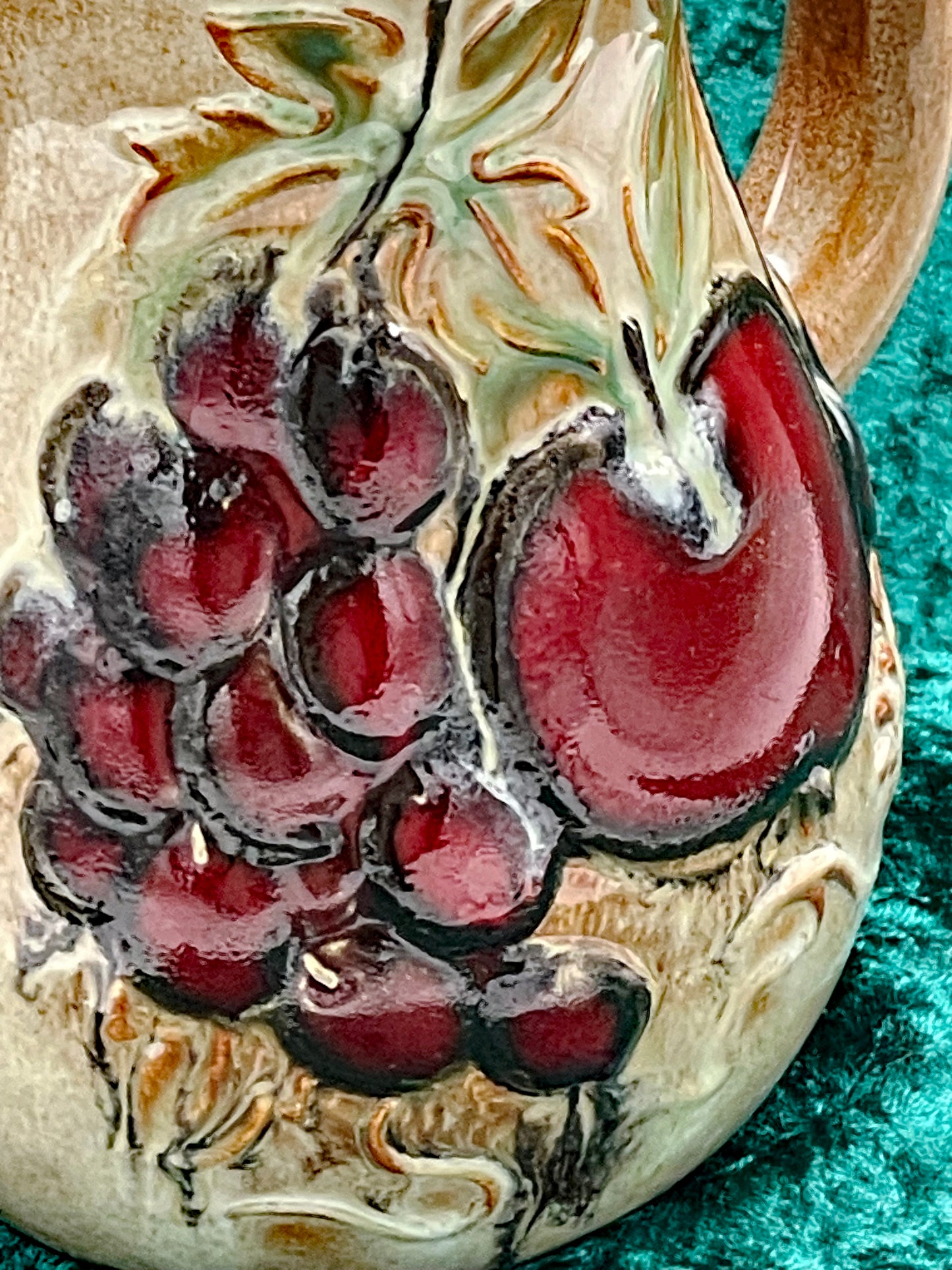 Close detail of the burgundy grapes and red apple relief decoration