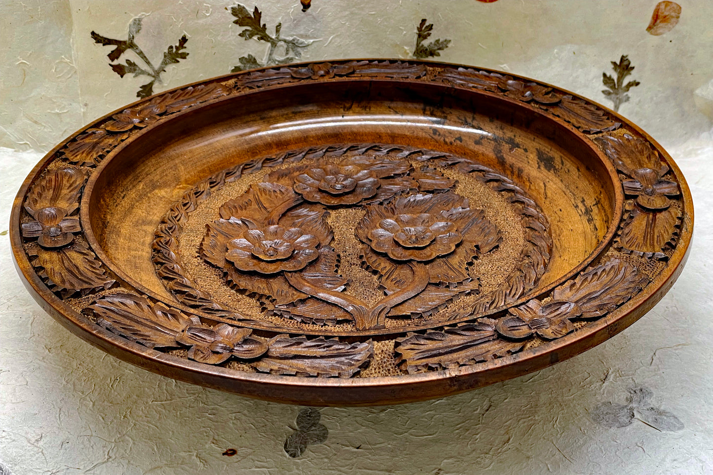 Hand-carved wooden plate showing lotus blossom center and leafy border