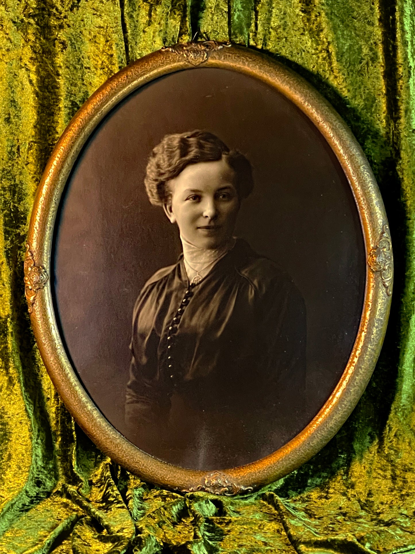 Vintage oval framed portrait of a woman displayed on green velvet